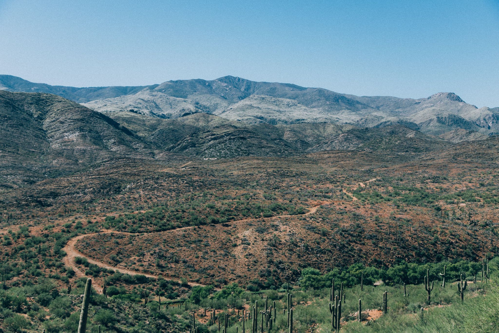 Aerial view of a winding dirt road through a vast desert valley with mountains. - Turkey Creek and Bumble Bee Road OHV Loop