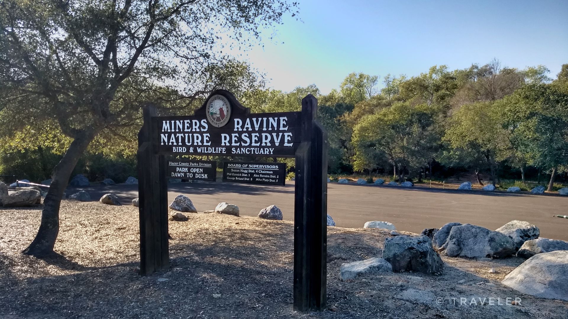 A wooden sign for a nature reserve stands by a paved area. - Miner's Ravine Trail – Miner's Ravine Nature Reserve loop from Roseville