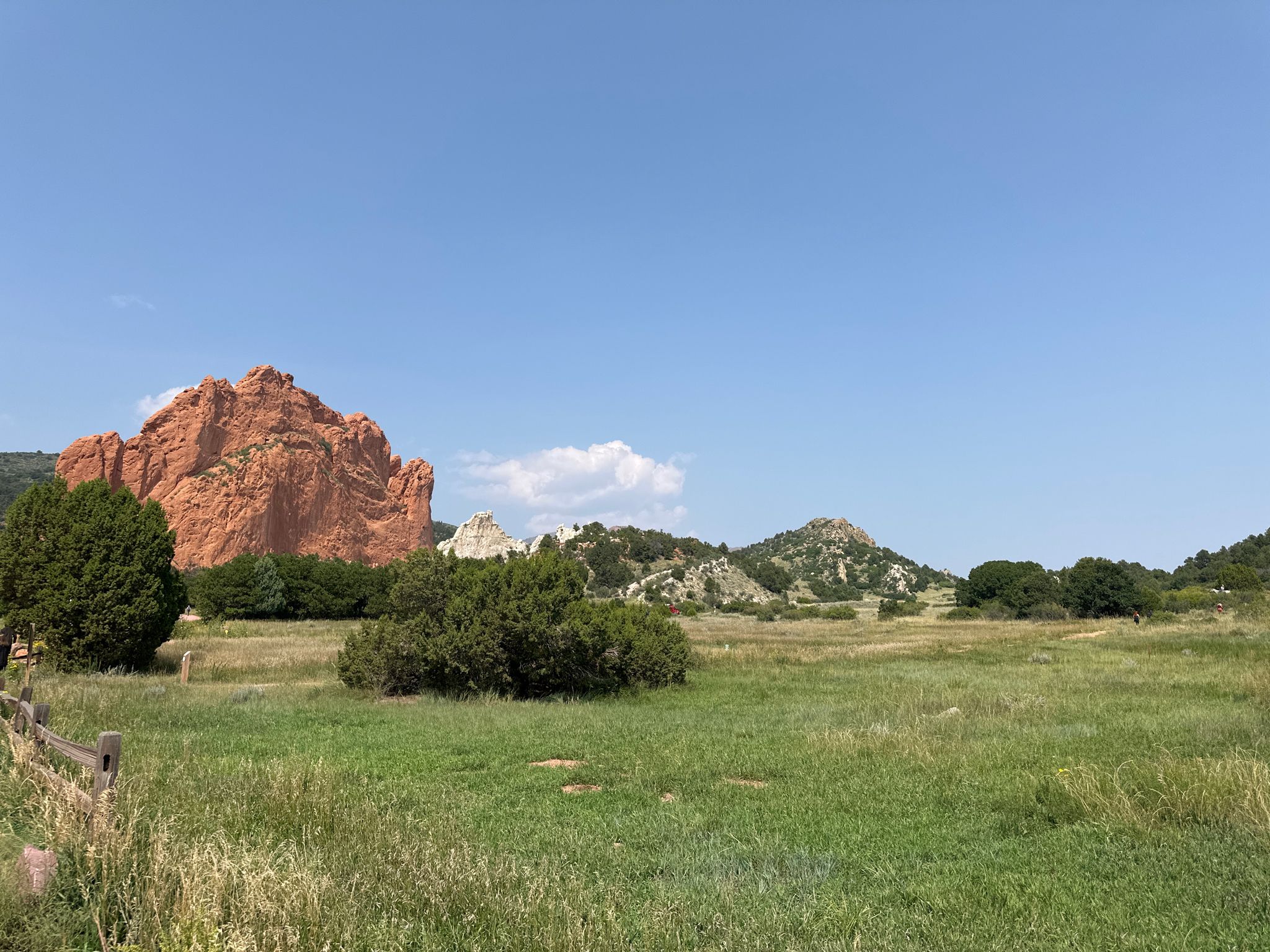 Large red rock formation stands prominently in a bright green field. - Colorado Front Range Trail and Pikes Peak Greenway Loop