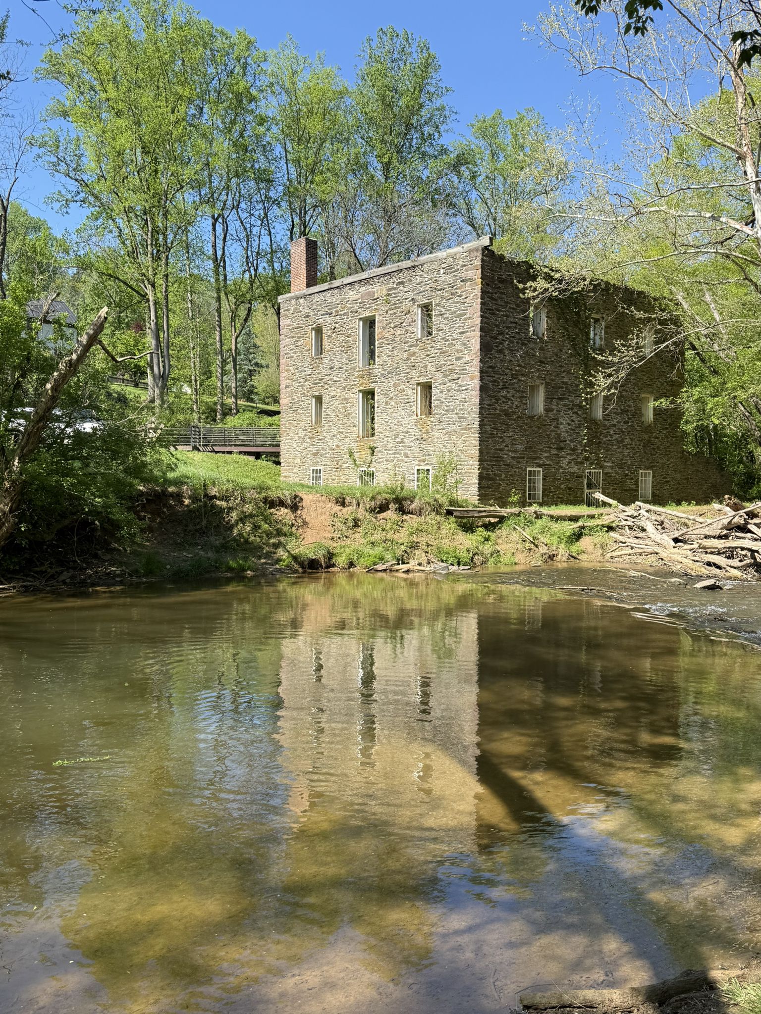 Stone building reflected in calm water under a clear, sunny sky. - Seneca Ridge and Seneca Greenway Trail Loop