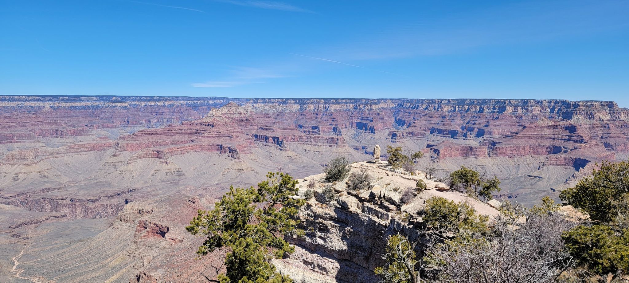 Expansive canyon vista under a clear blue sky, with rocky foreground. - Shoshone Point Trail