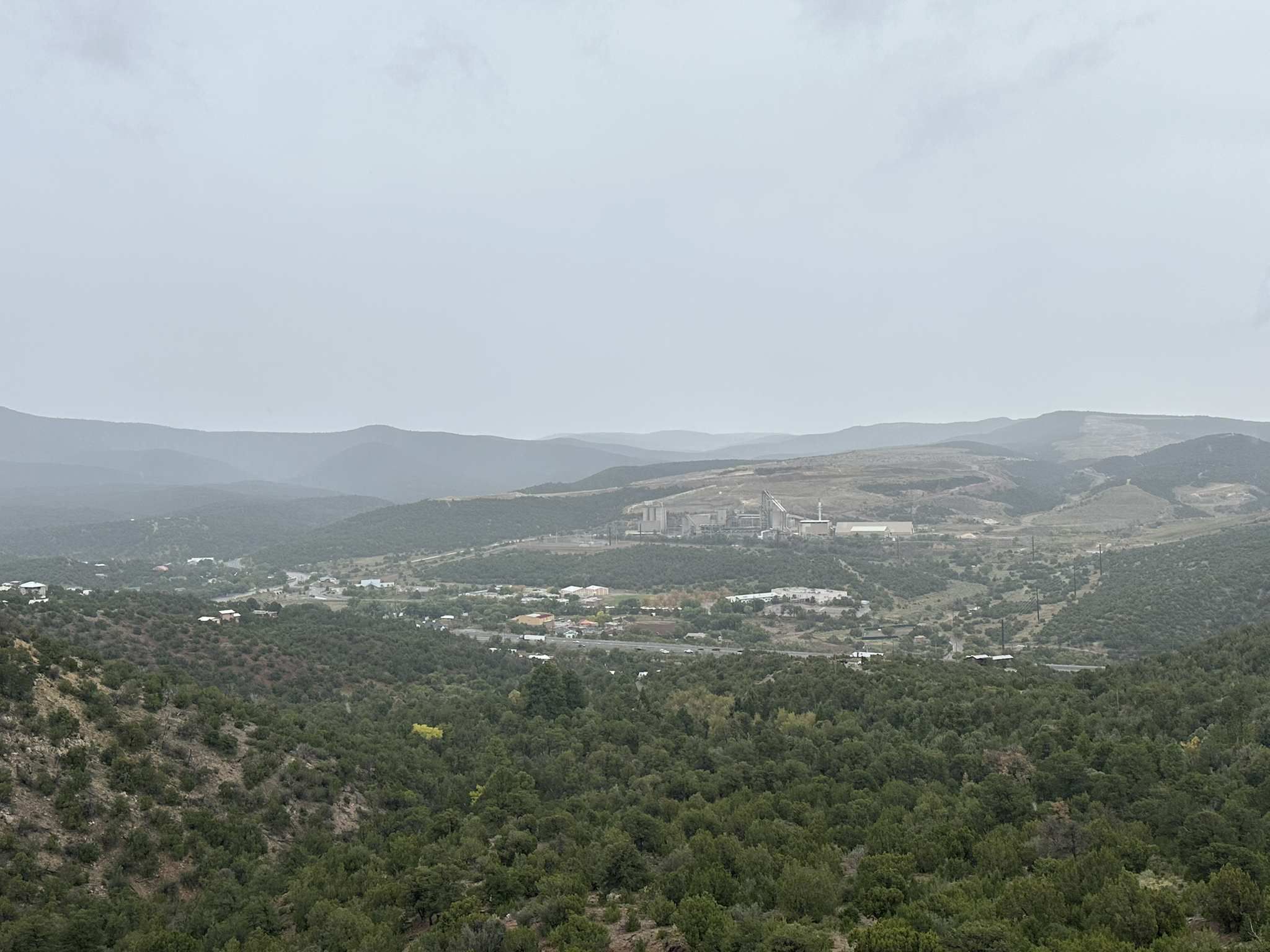Hilly landscape with a town and industrial structures under an overcast sky. - Carlito Springs Loop Trail