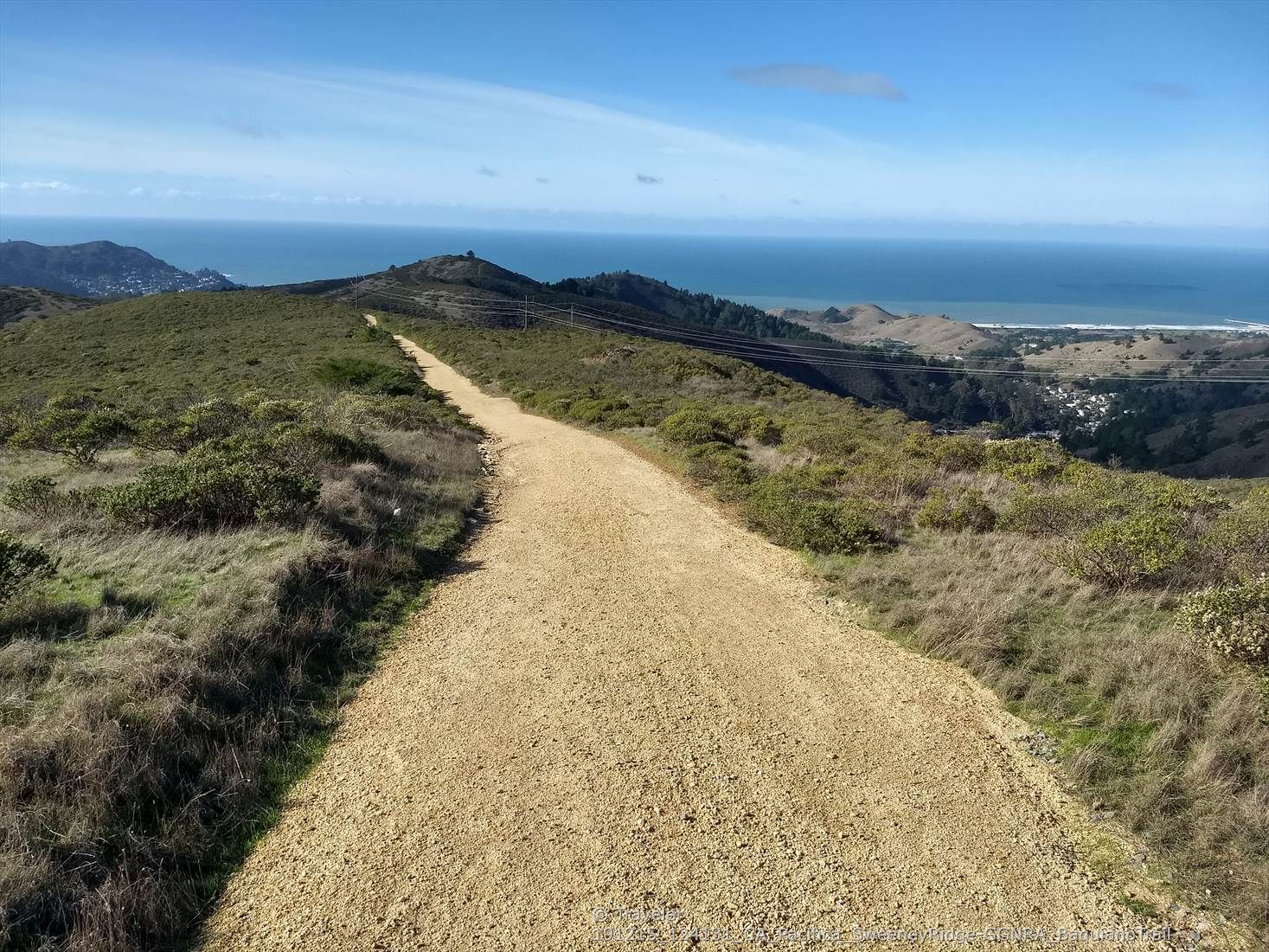 A wide dirt path leads over green hills towards a distant ocean. - Mori Point Headlands – Rockaway Beach loop from Milagra Ridge