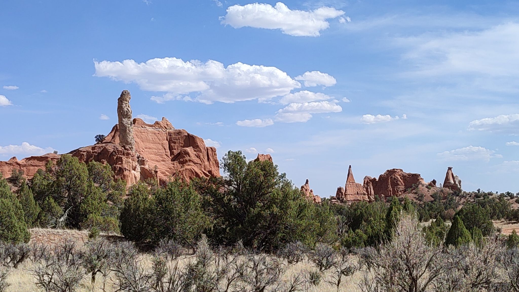 Red rock formations and green trees under a partly cloudy sky. - Ballerina Spire – Panorama Point loop from Kodachrome Basin State Park