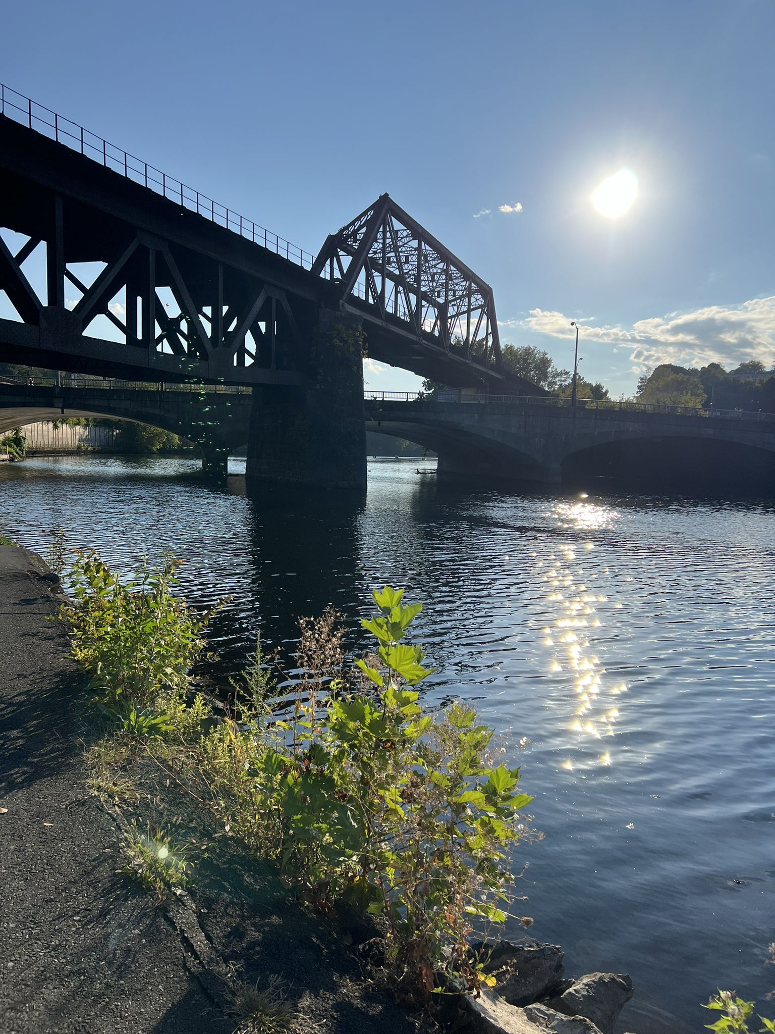 A large metal bridge spans a river with sun reflecting on water. - Bixlers Bluff – Billy's Downtown Diner loop from Easton