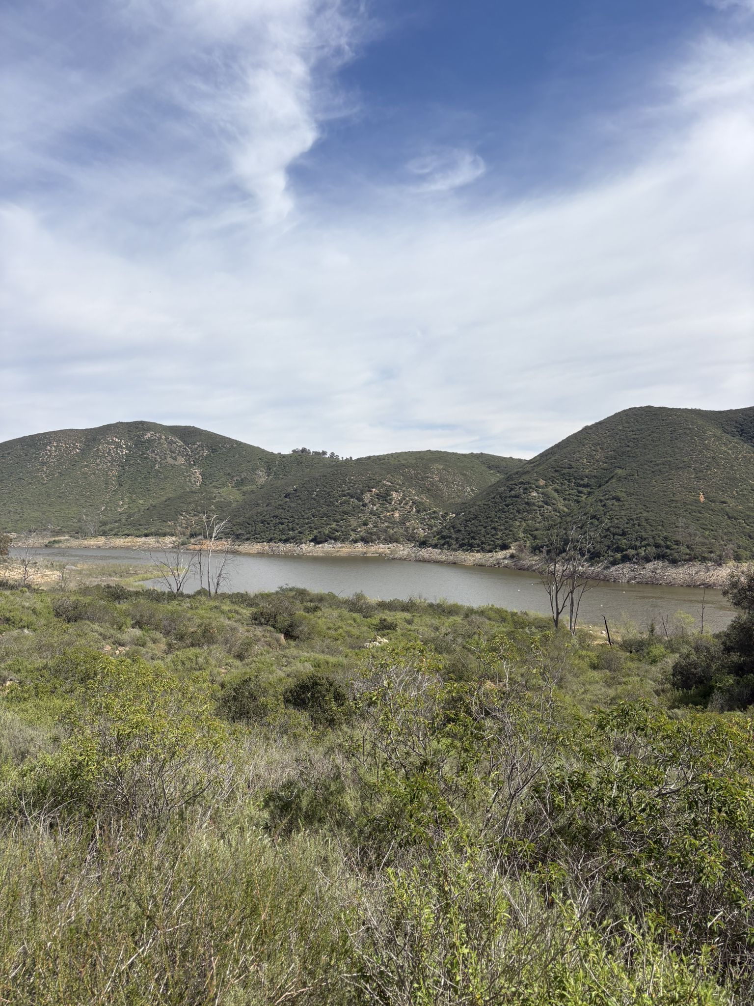 Green hills surround a calm lake under a bright, cloudy sky. - Hodges Dam – Lake Hodges Trail loop from San Elijo Hills