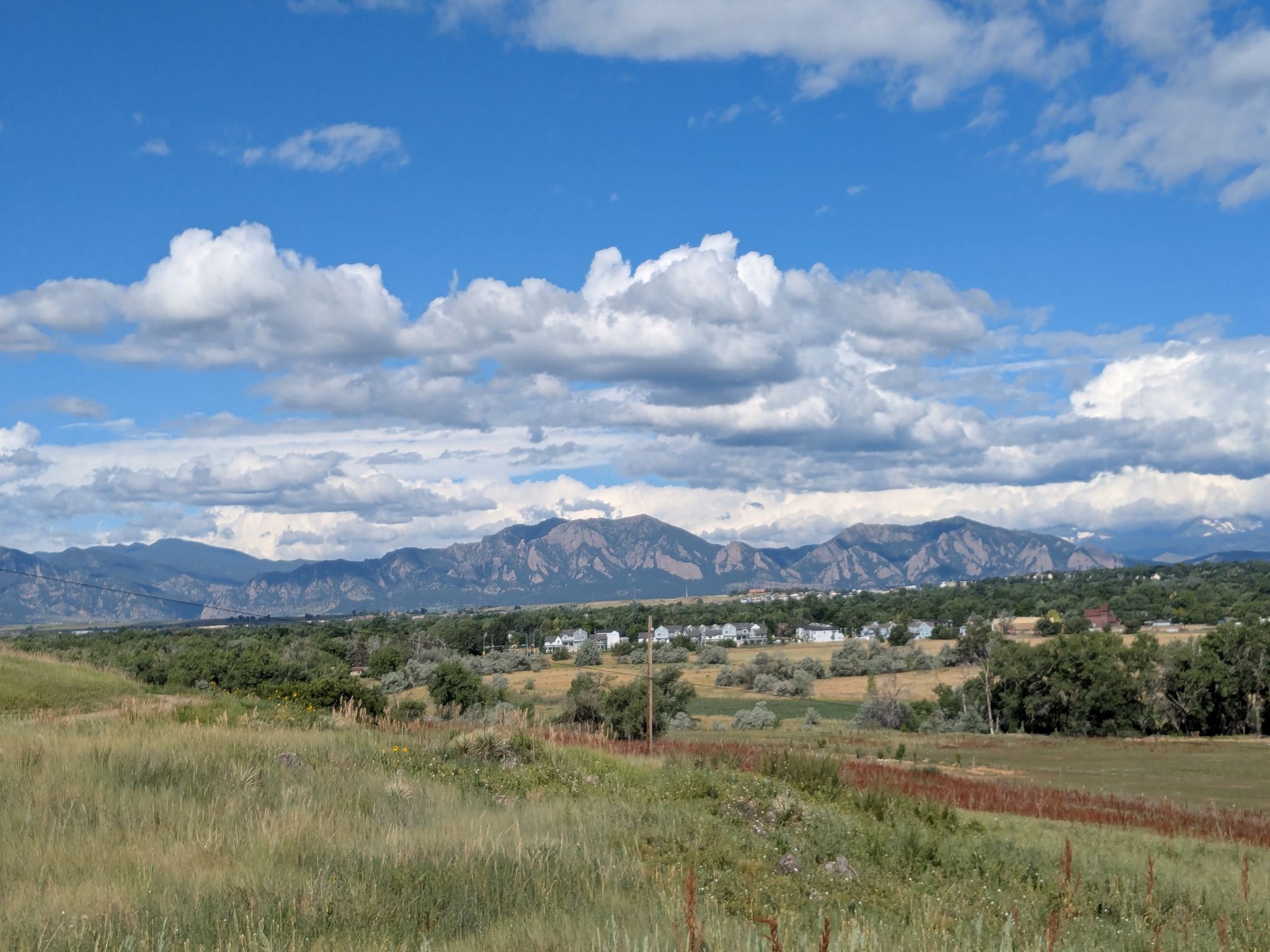A wide view of distant mountains over a field under a cloudy sky. - Aquarius Open Space – Sterns Lake loop from Broomfield High School