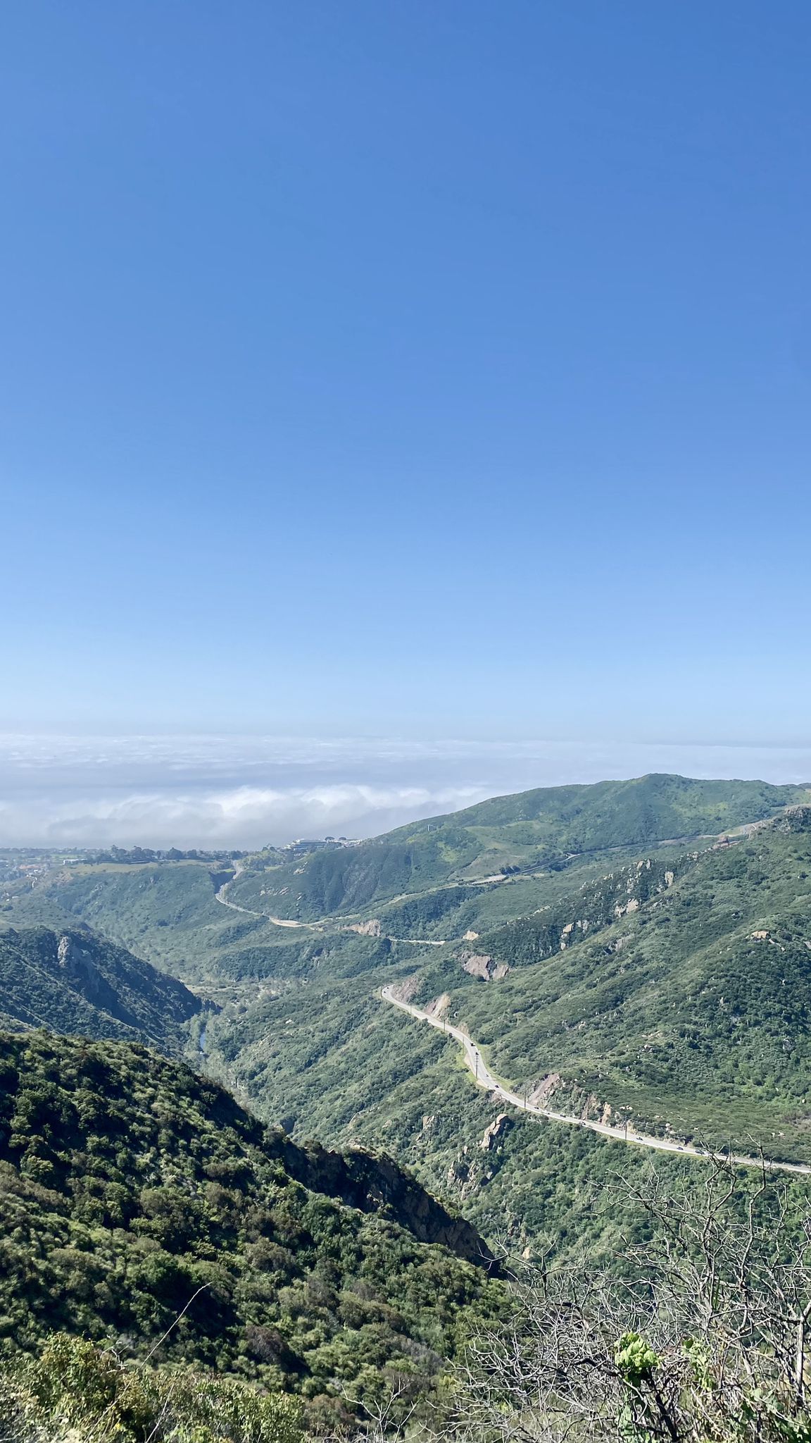 Expansive view of a deep mountain valley with a winding road and green slopes. - Wild Walnut Park – Mulholland Highway loop from Louisville High School
