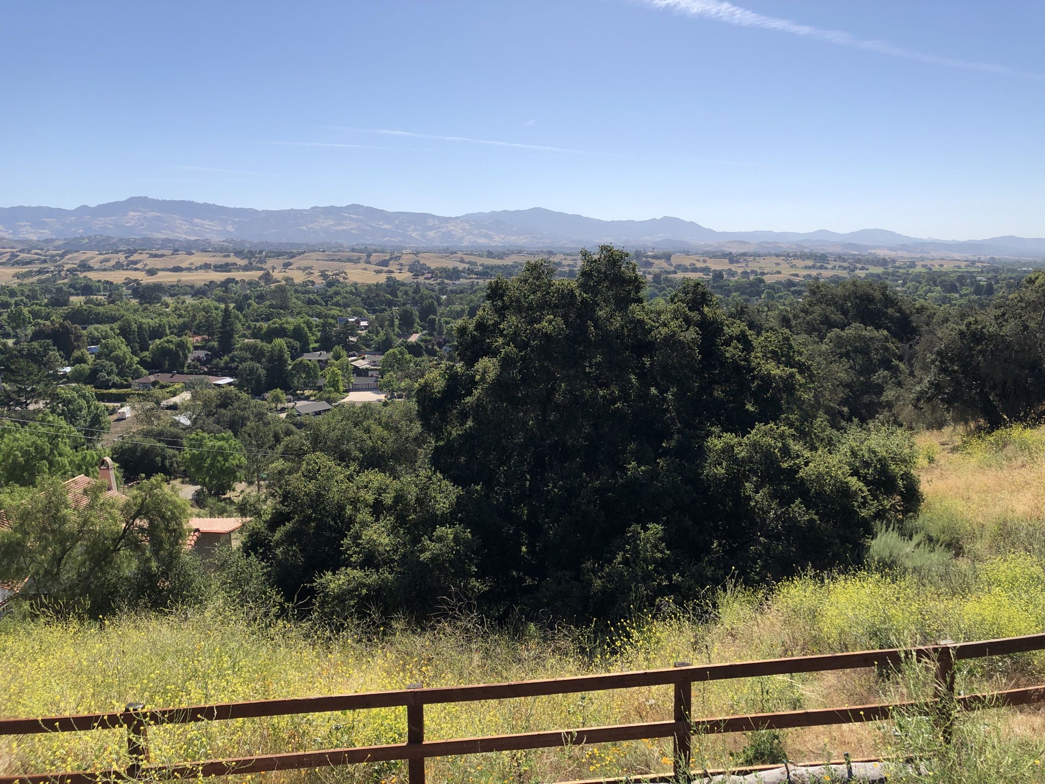 Panoramic view of a lush green valley with a distant town and hills. - Dan Henry Bike Route – Solvang loop from Solvang