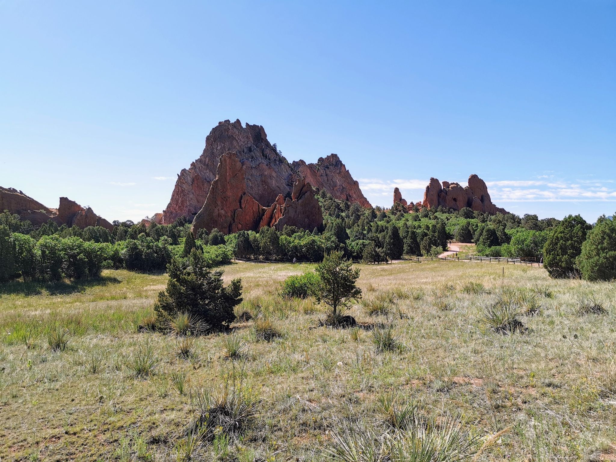 Expansive grassy field with distant red rock formations under a clear blue sky. - Garden of the Gods loop from Garden of the Gods