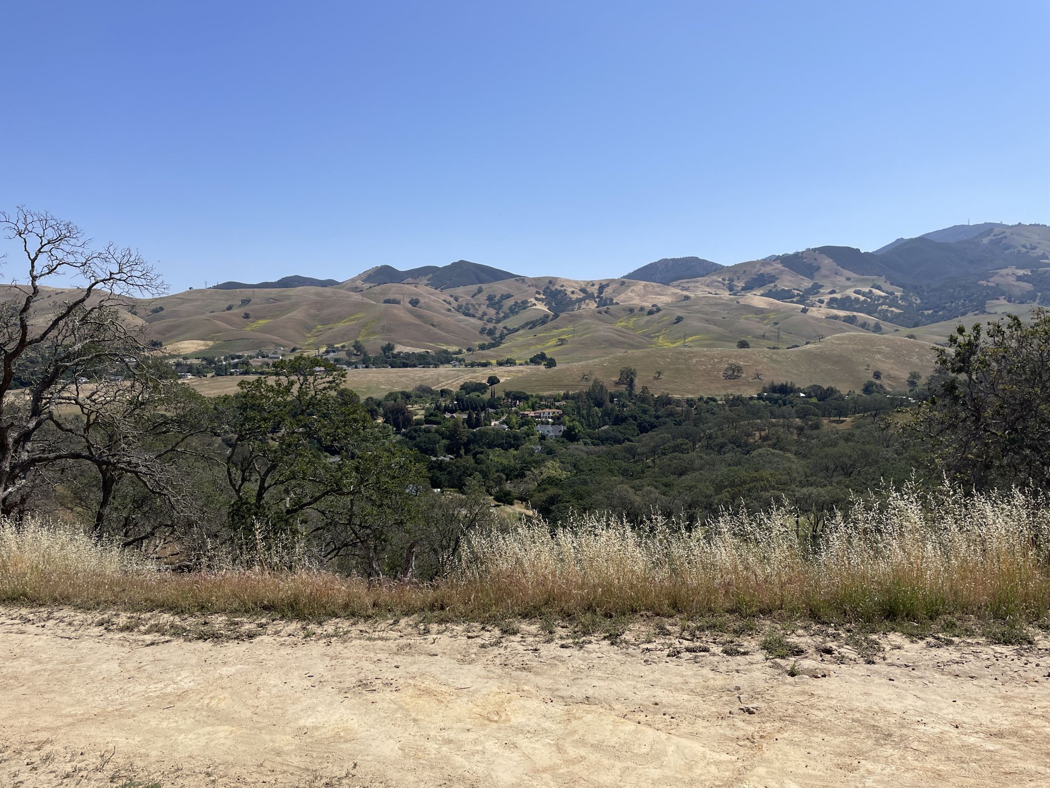 Clear day over dry hills, green valley, and foreground dirt path. - Hanna Grove and Costanoan Trail Loop