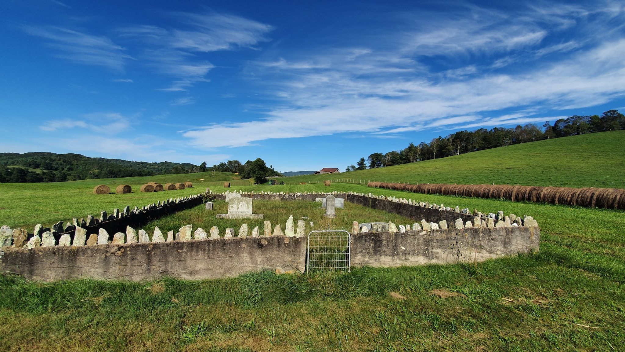 Stone-walled enclosure in a sunny green field with hay bales and rolling hills. - Smart View Recreation Area to Roanoke Mountain Loop Road