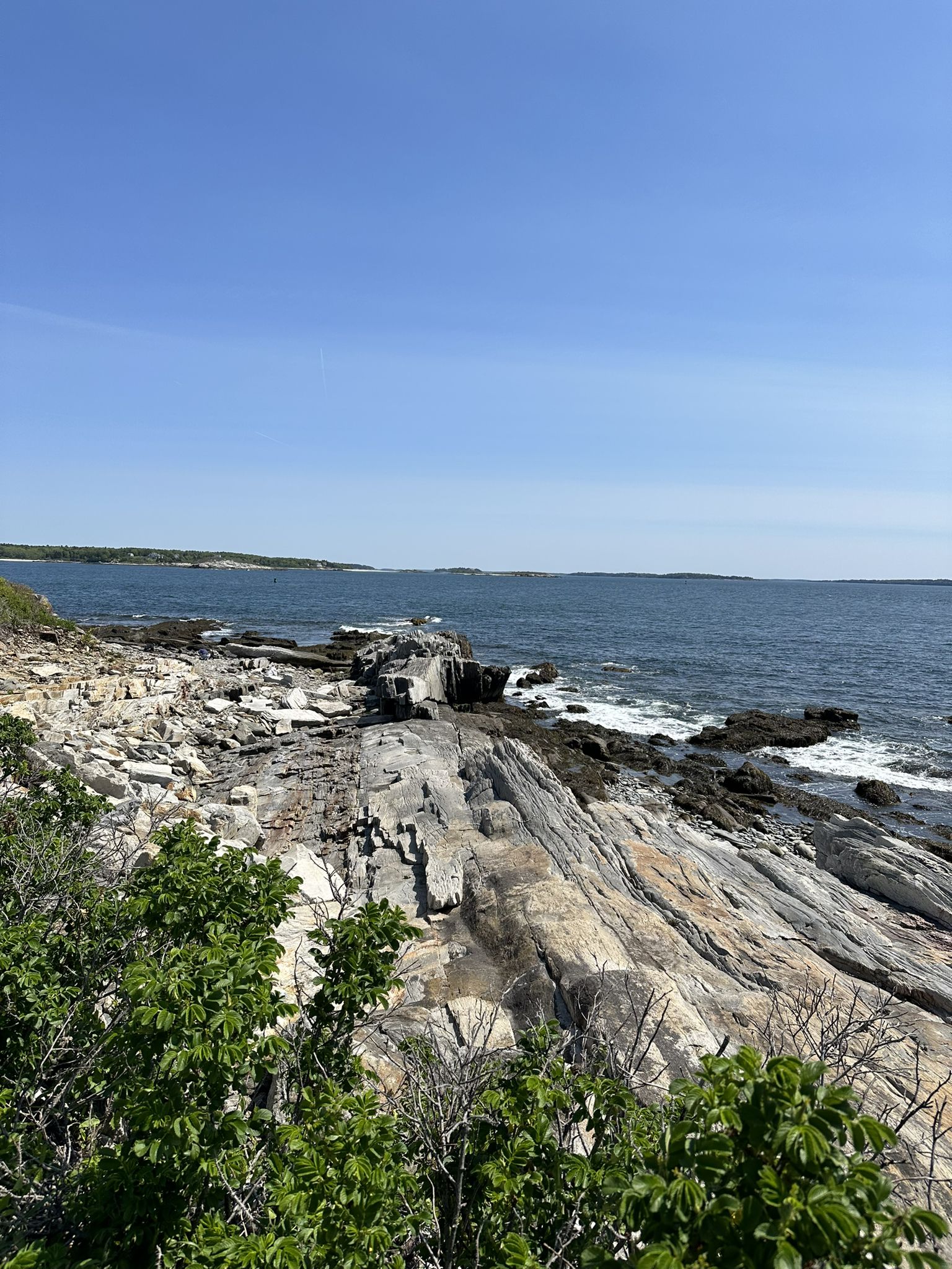 Rocky coastline with ocean waves under a clear blue sky on a bright day. - Peaks Island Land Preserve – Bench With Ocean View loop from Peaks Island