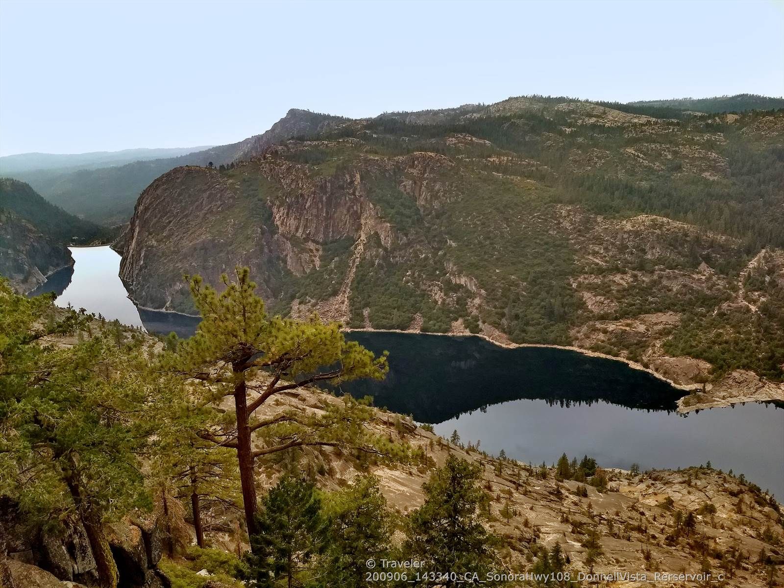 Dark lake surrounded by steep, forested mountains under a cloudy sky. - Donnell Vista Trail