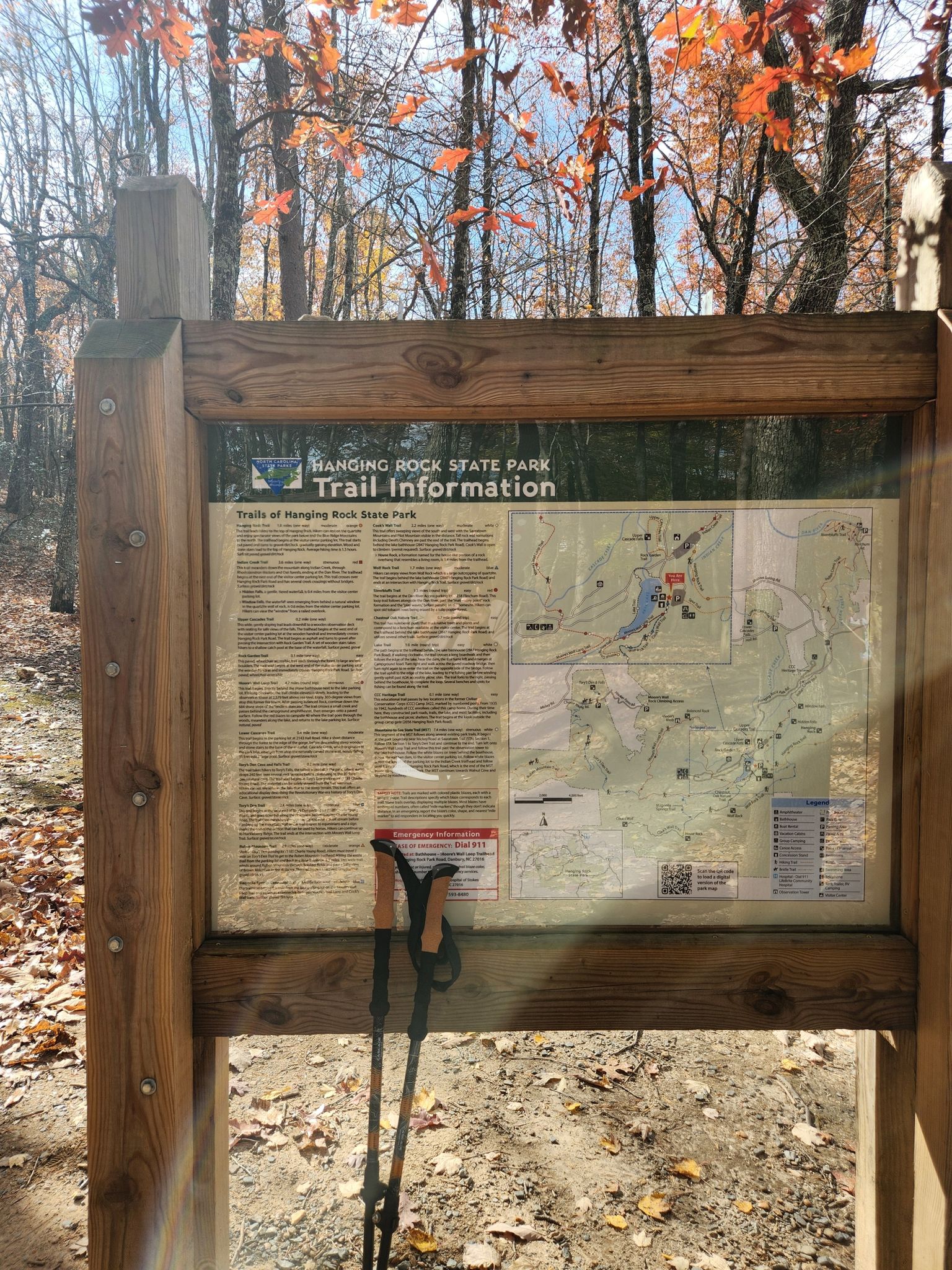 Wooden trail information board with hiking poles, surrounded by autumn trees. - Cooks Wall Trail
