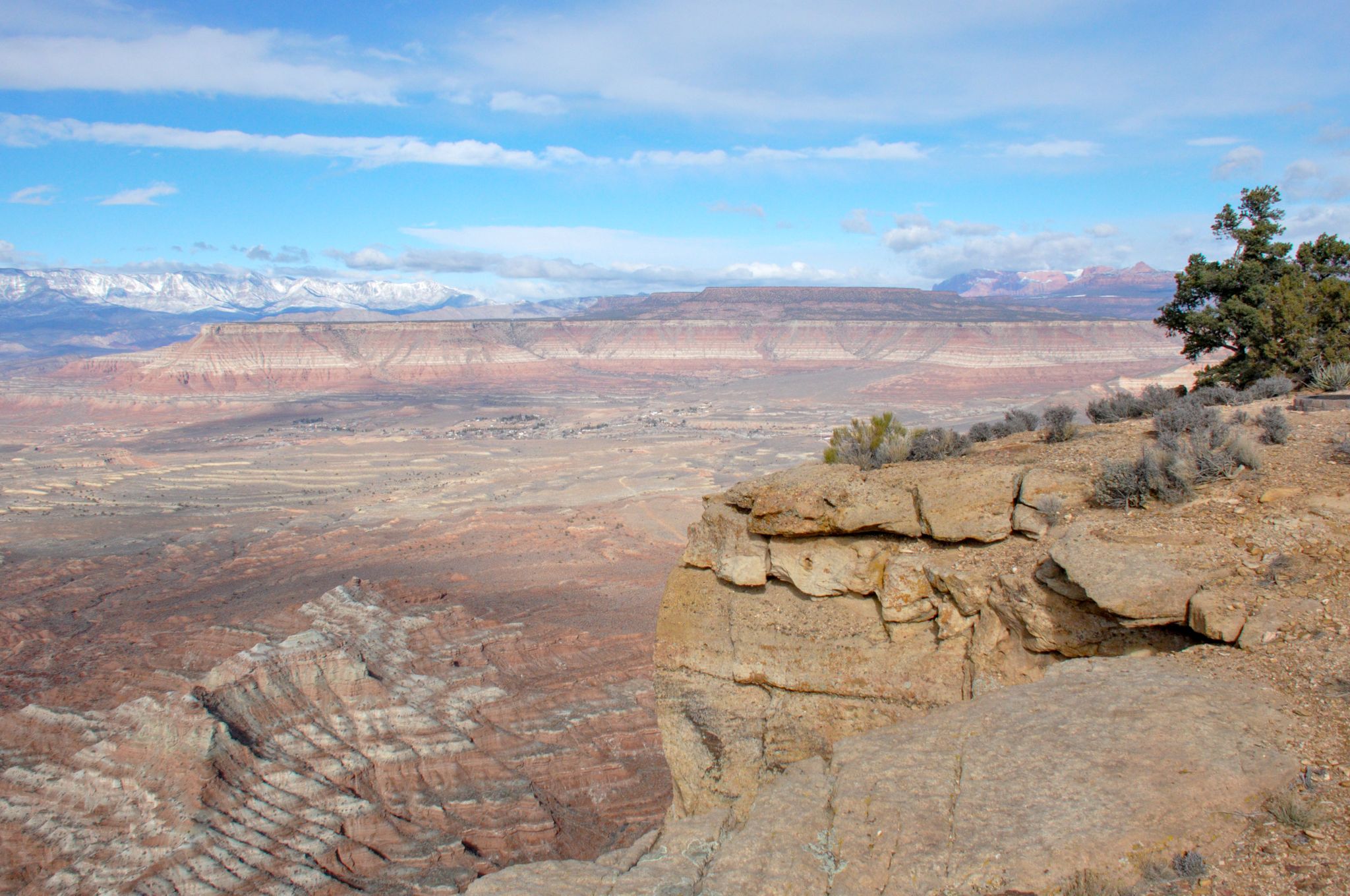 Vast desert canyon landscape with red rock cliffs under a bright blue sky. - Windmill Trail Loop