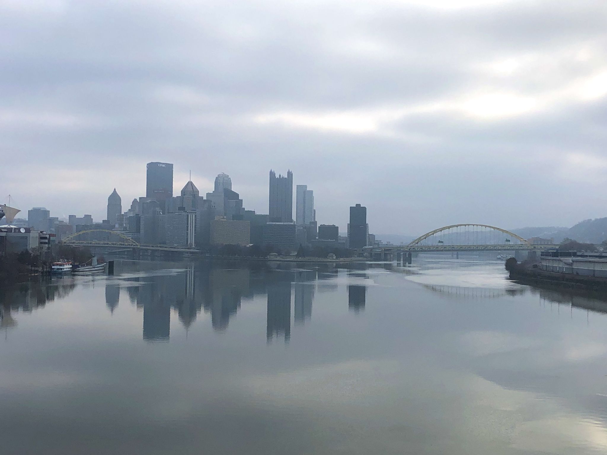 Overcast city skyline reflected in a calm river with an arched bridge. - Heinz Factory Complex – North Shore Riverfront Park loop from Gateway
