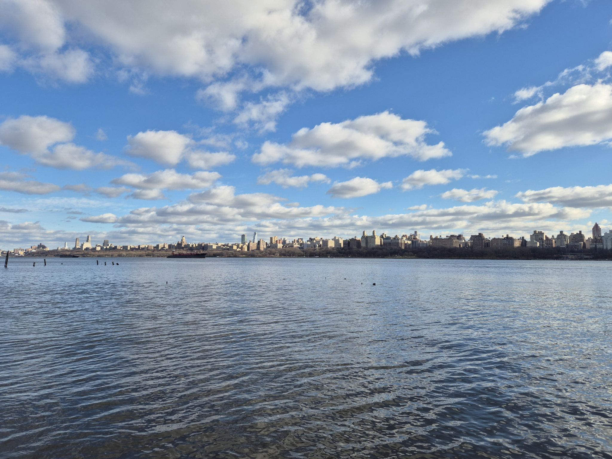 Wide river with distant city skyline under a bright blue, cloudy sky. - Port Imperial Waterfront loop from 2nd Street