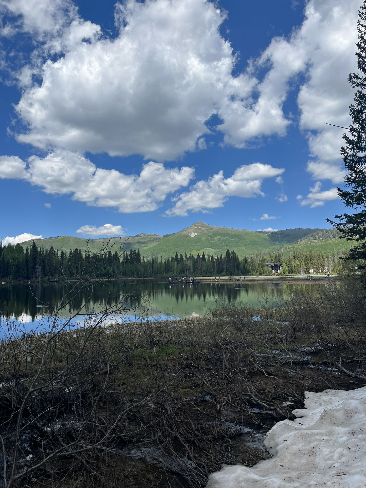 Serene lake with green mountains, cloudy sky, and snow on the shore. - Silver Lake Nature Trail