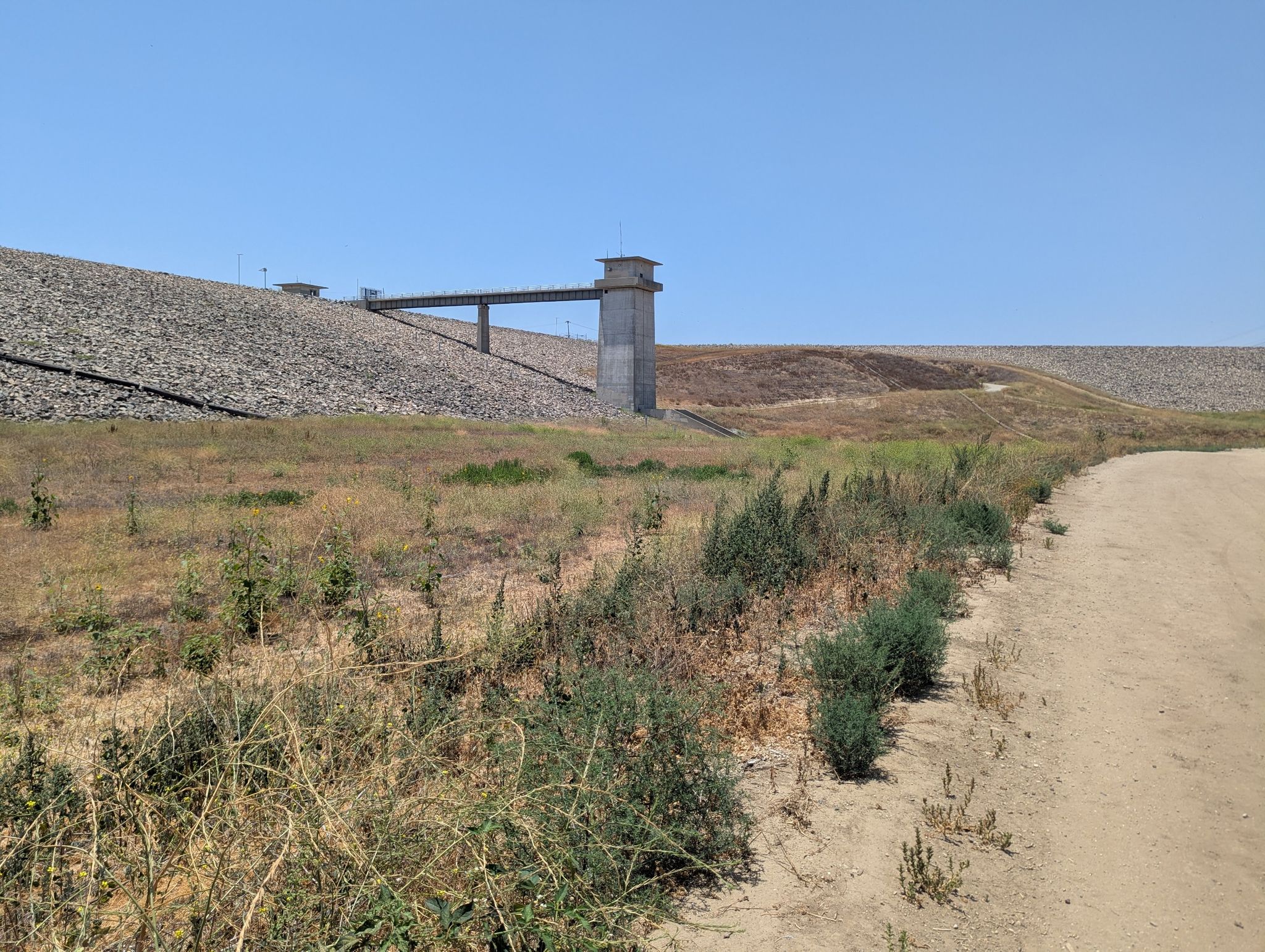 A large dam wall with a concrete tower and bridge under a clear sky. - Carbon Canyon Nature and Redwood Trail Loop
