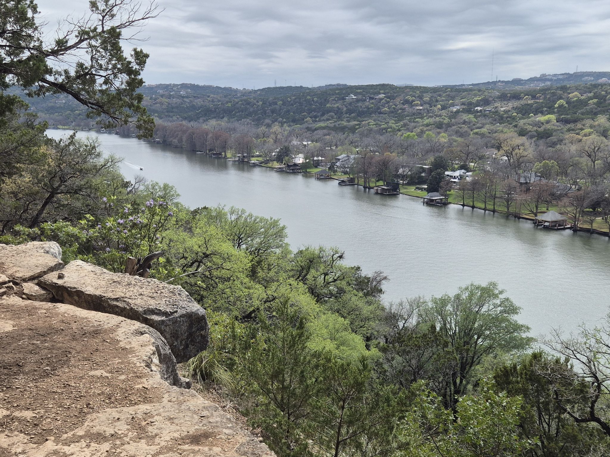 Overcast view of a wide river winding through green forested hills. - Emma Long Cliff Loop
