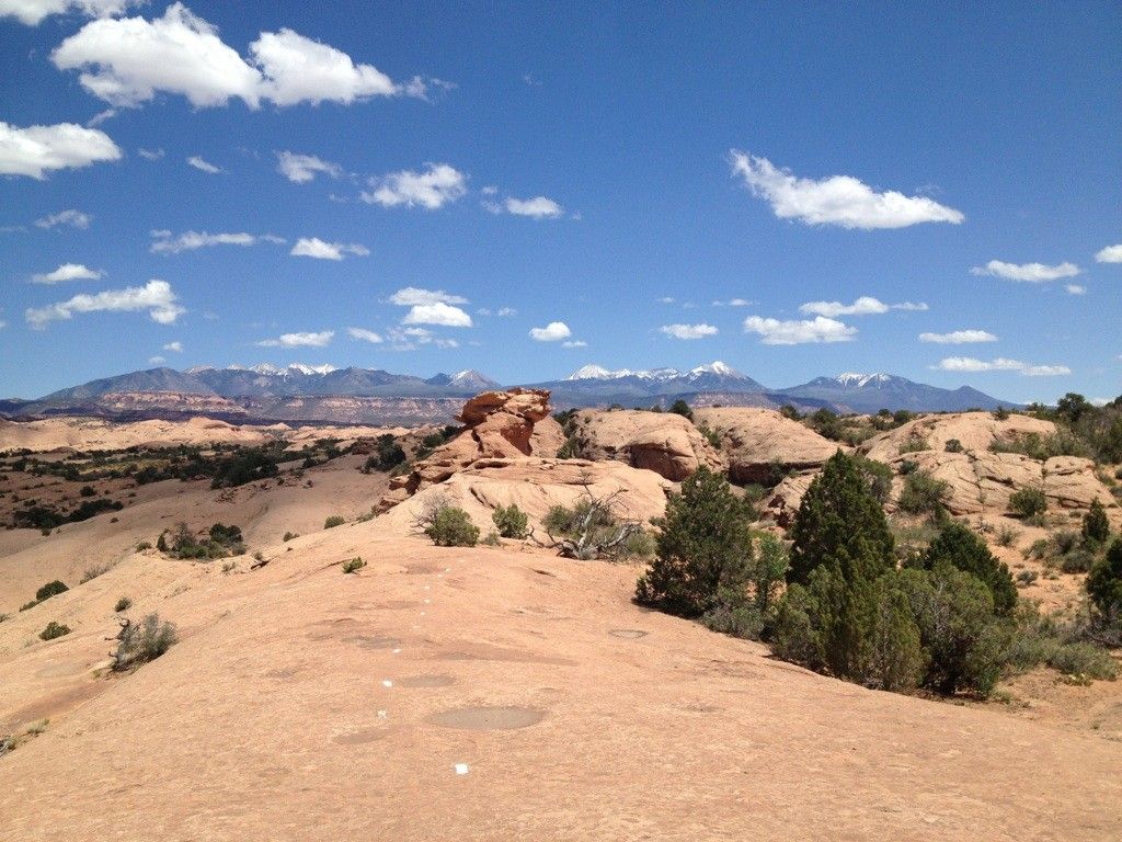 Rocky desert landscape with distant snow-capped mountains under a blue sky. - Slickrock Trailhead – Slickrock Practice Loop loop from SFRA Loop D - Datura Campground