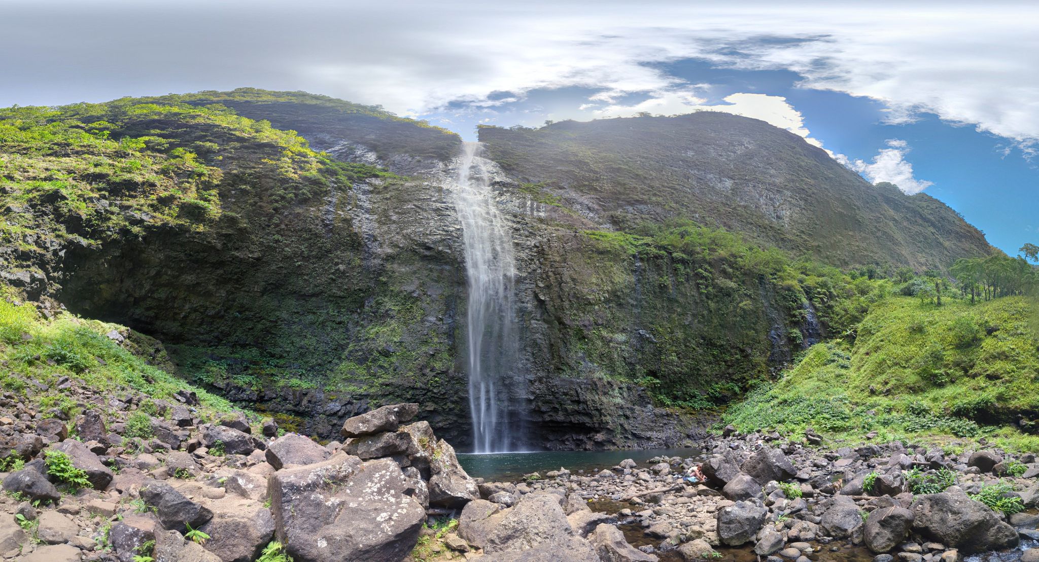 A tall waterfall plunges into a pool, surrounded by rocky cliffs and green foliage. - Hanakapi'ai Falls loop from Haena State Park
