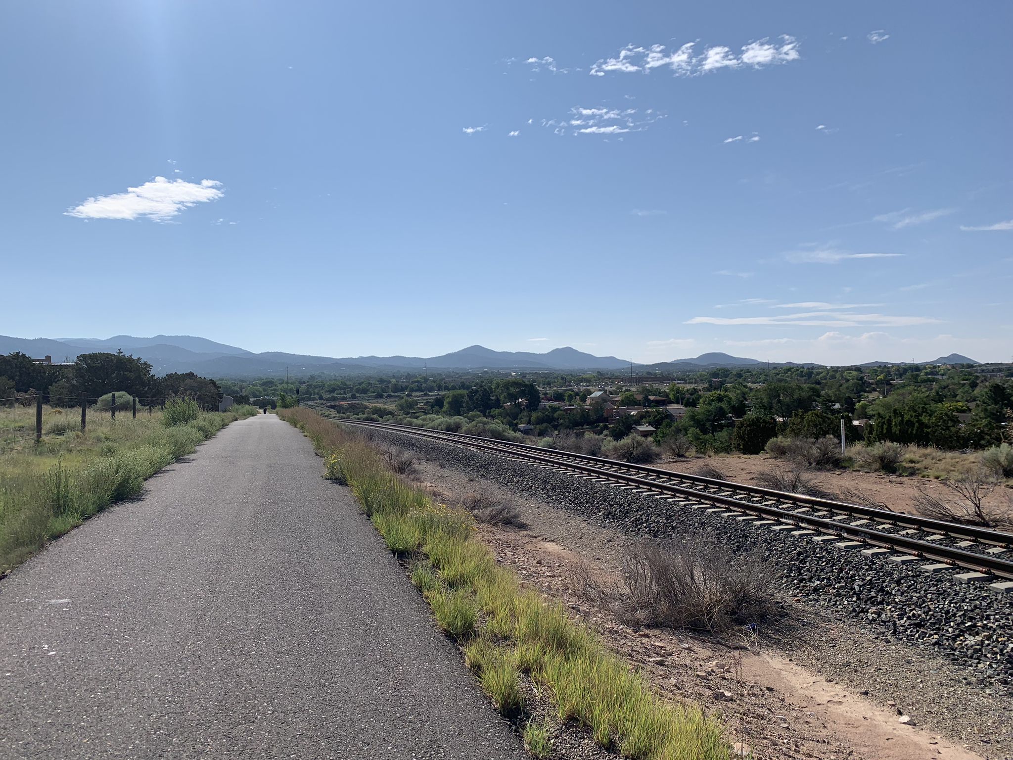 Paved path runs parallel to railroad tracks through a sunny, arid landscape. - Santa Fe River Trail – Frenchy's Falls loop from Museum of International Folk Art