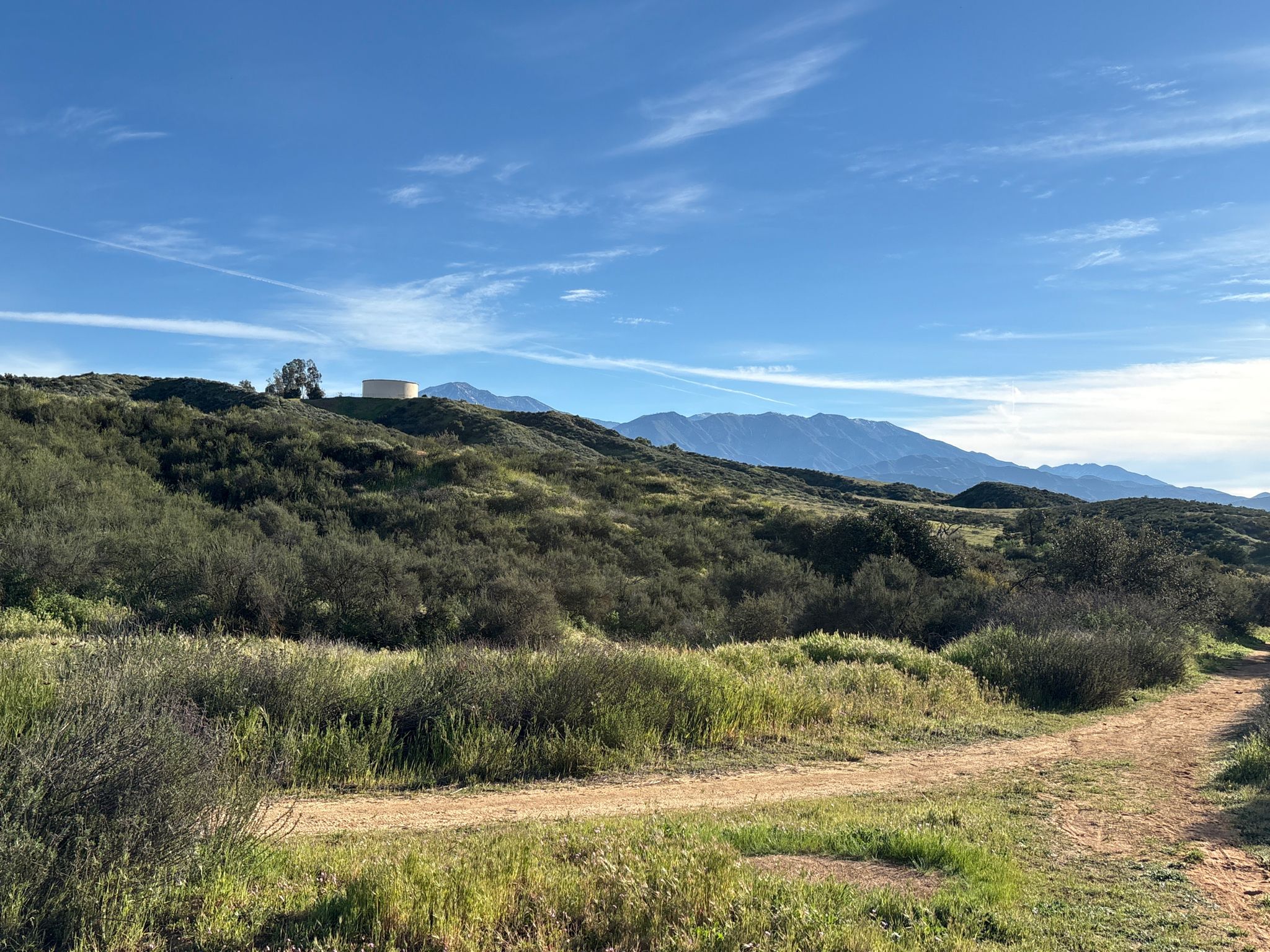 Dirt path through green hills with distant mountains under a clear blue sky. - Oakmont and Oakridge Trail