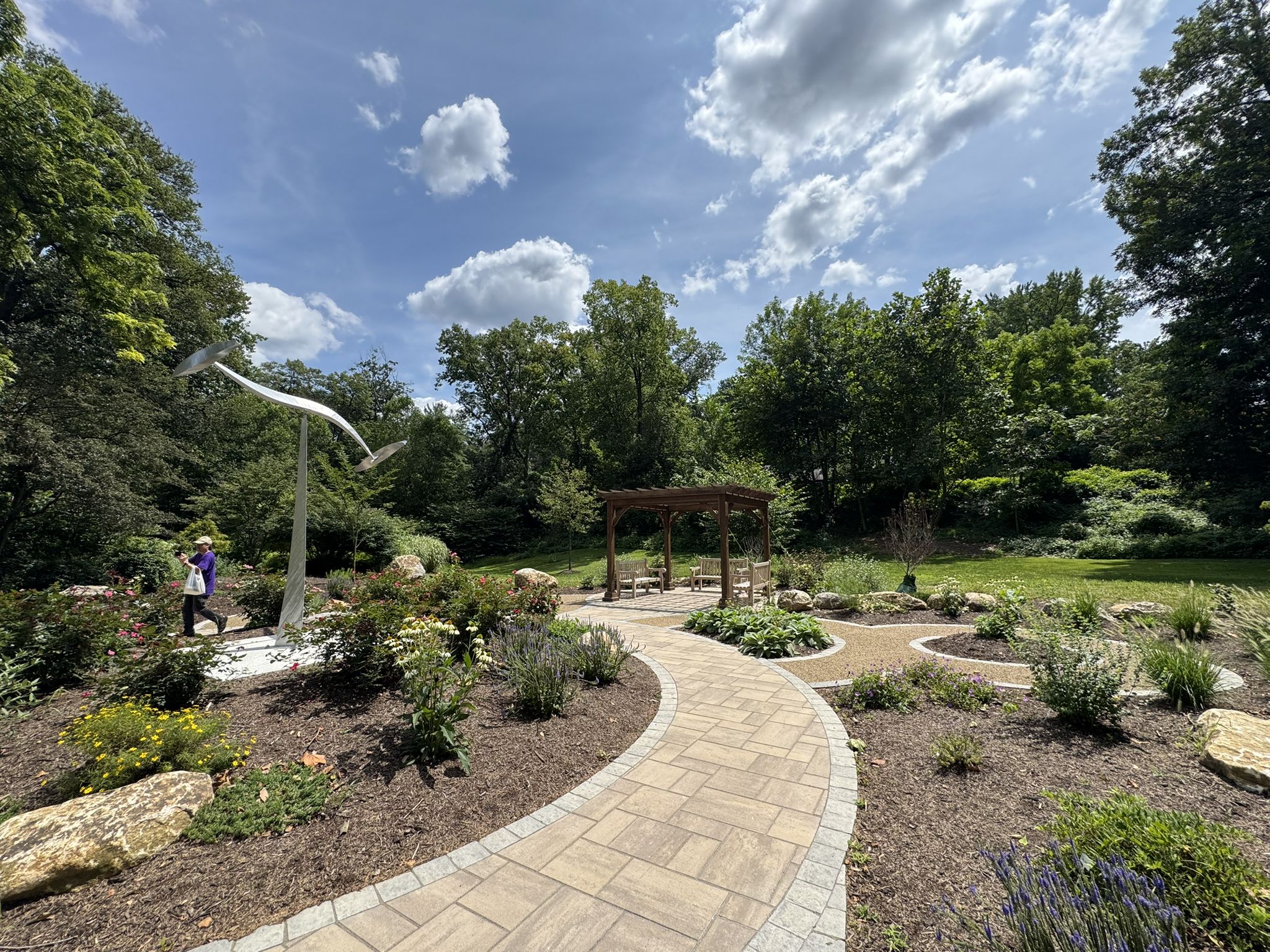A person walks on a winding garden path with a pergola and sculpture. - Tulpehocken Creek/Lake Ontelaunee loop