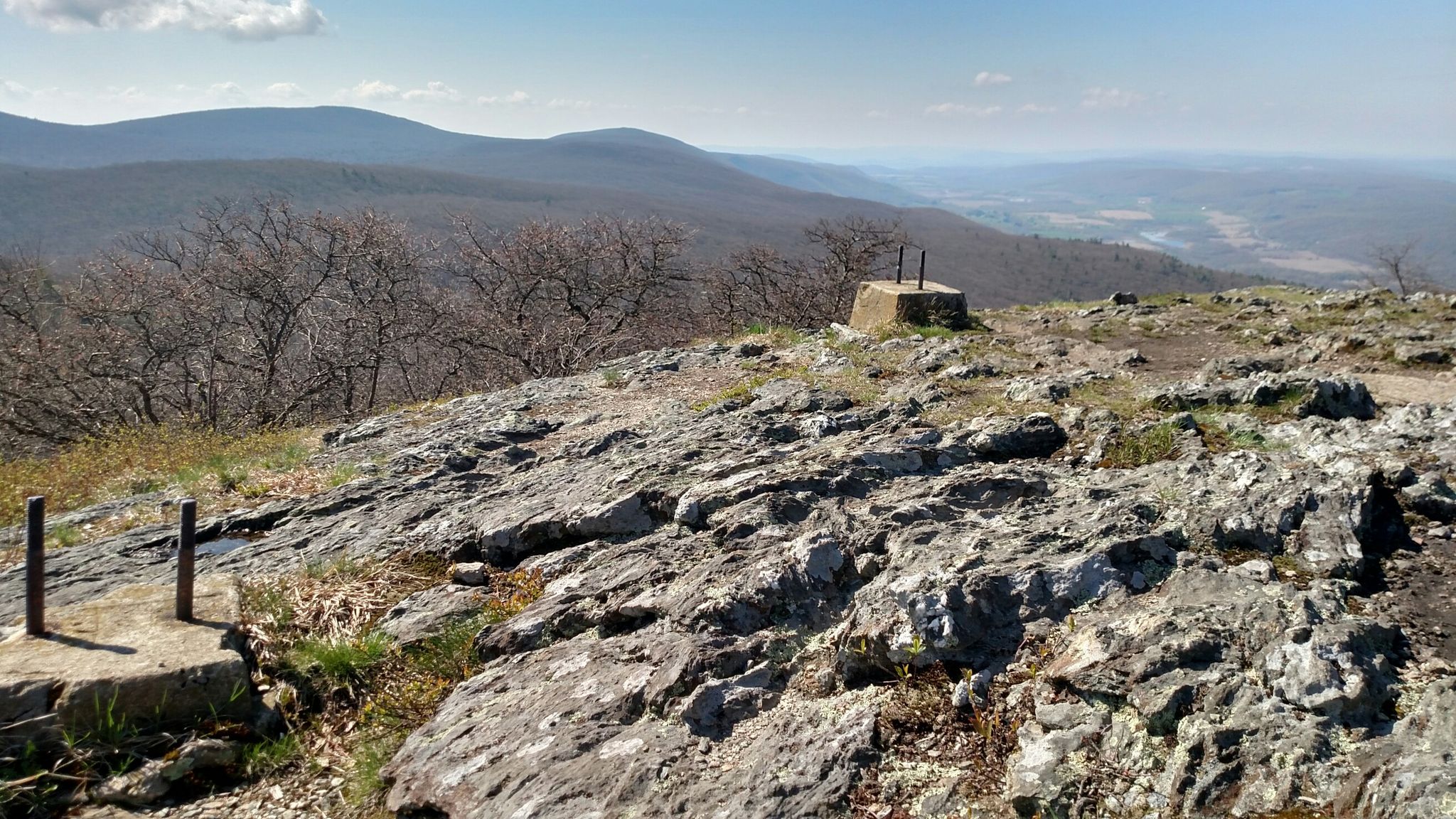 Rocky mountain summit with concrete markers, distant mountains, and valley under clear sky. - Alander Mountain via South Taconic Trail