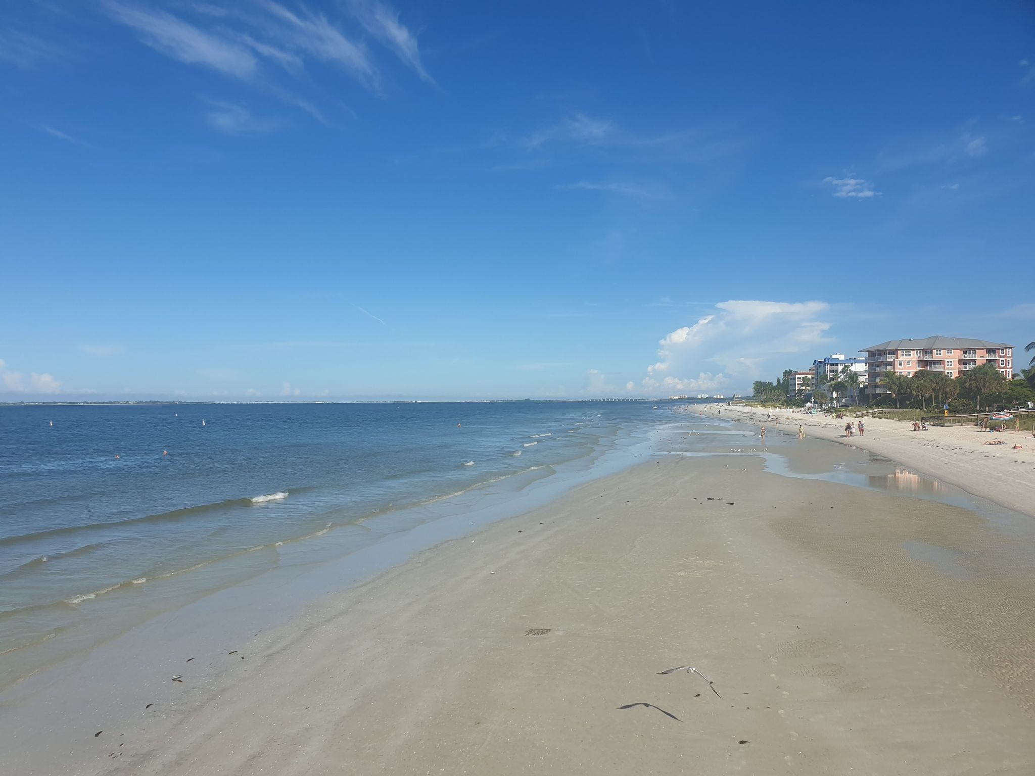 Expansive sandy beach next to the ocean, with distant buildings under a blue sky. - Bowditch Point Park