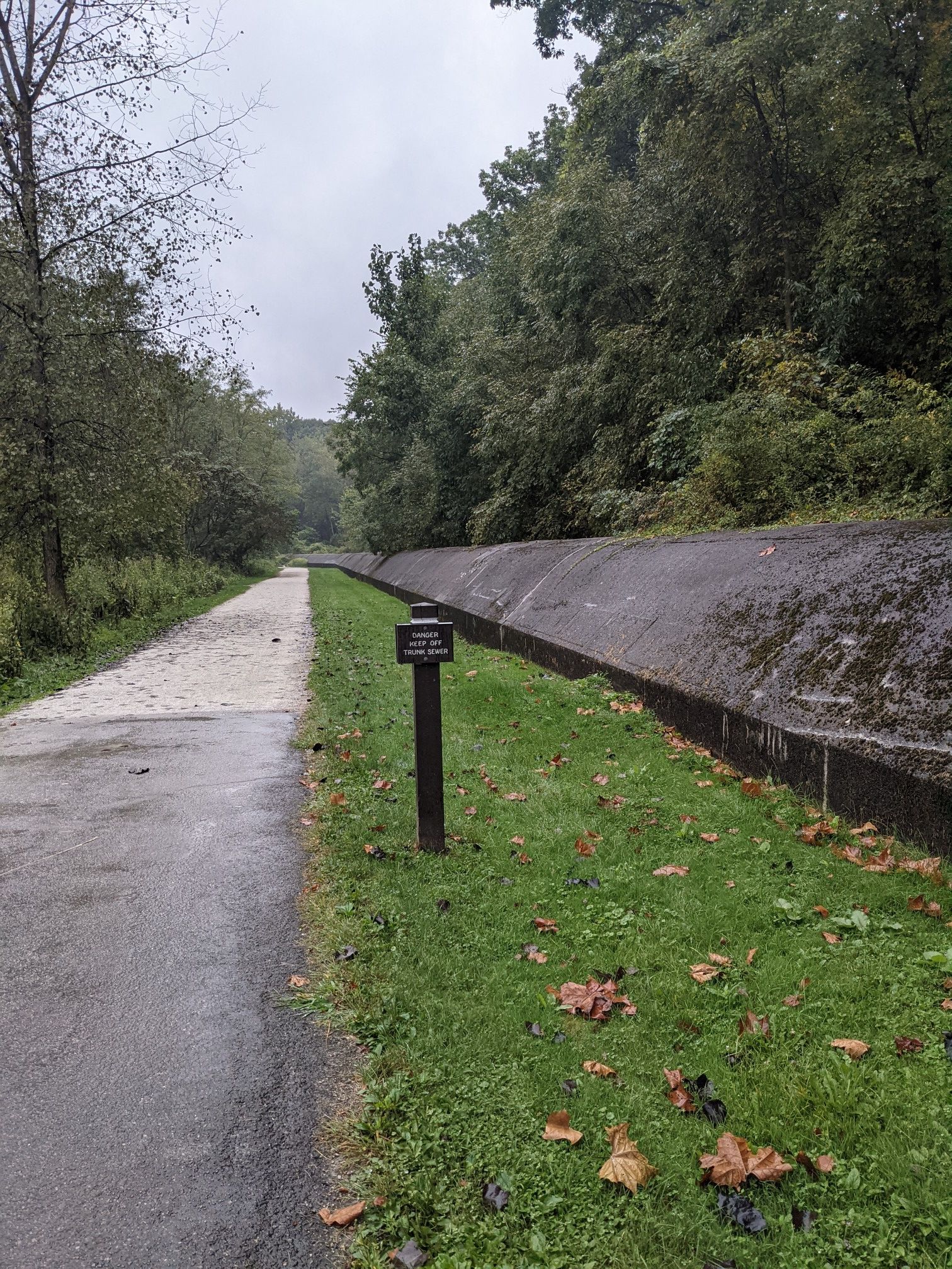 Paved path next to a concrete channel and grassy bank, under an overcast sky. - Ohio and Erie Canal Towpath: Memorial Parkway