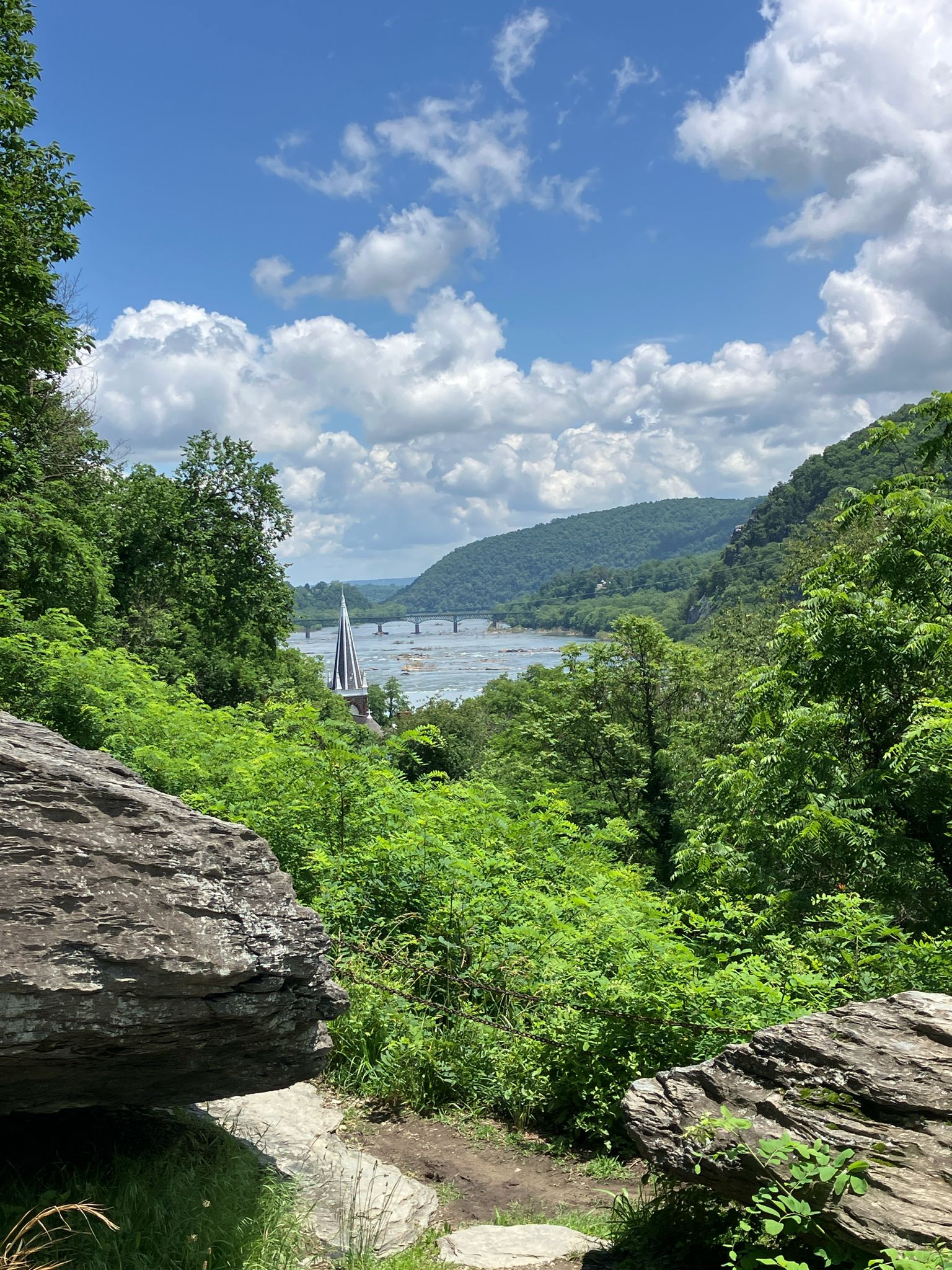 Sunny view of a river valley with a church steeple and distant bridge. - Harpers Ferry Lower Town Trail Loop