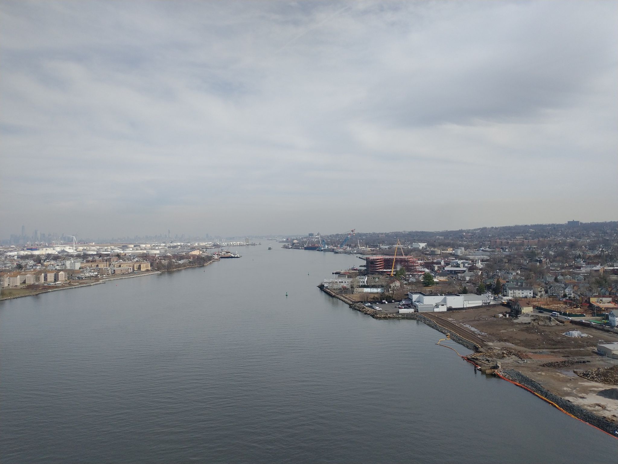 Wide river flowing between urbanized banks under a cloudy sky. - East Coast Greenway and 9/11 Trail Loop