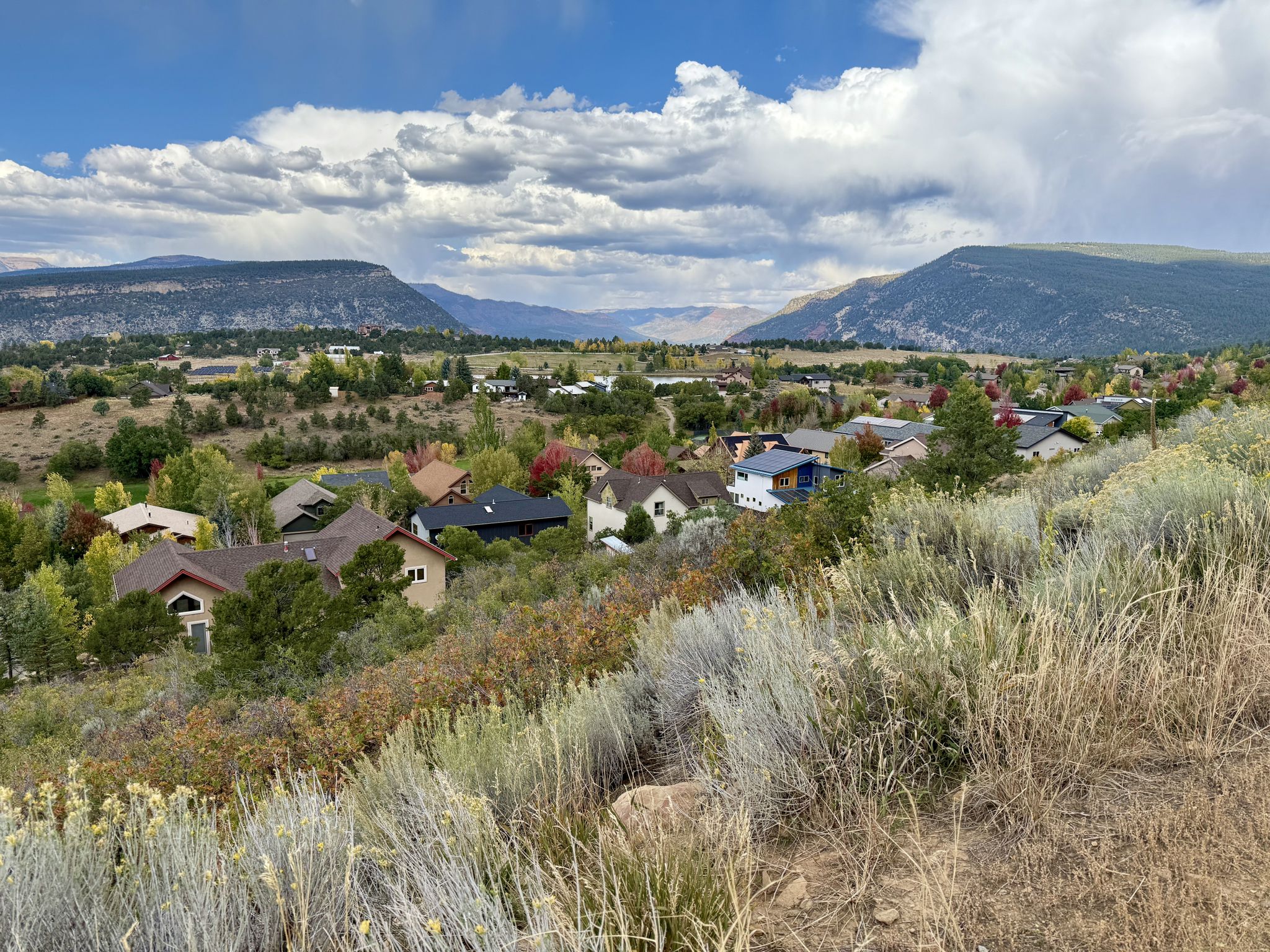 Valley view with houses, colorful trees, and distant mountains under cloudy sky. - Raiders Ridge Trail