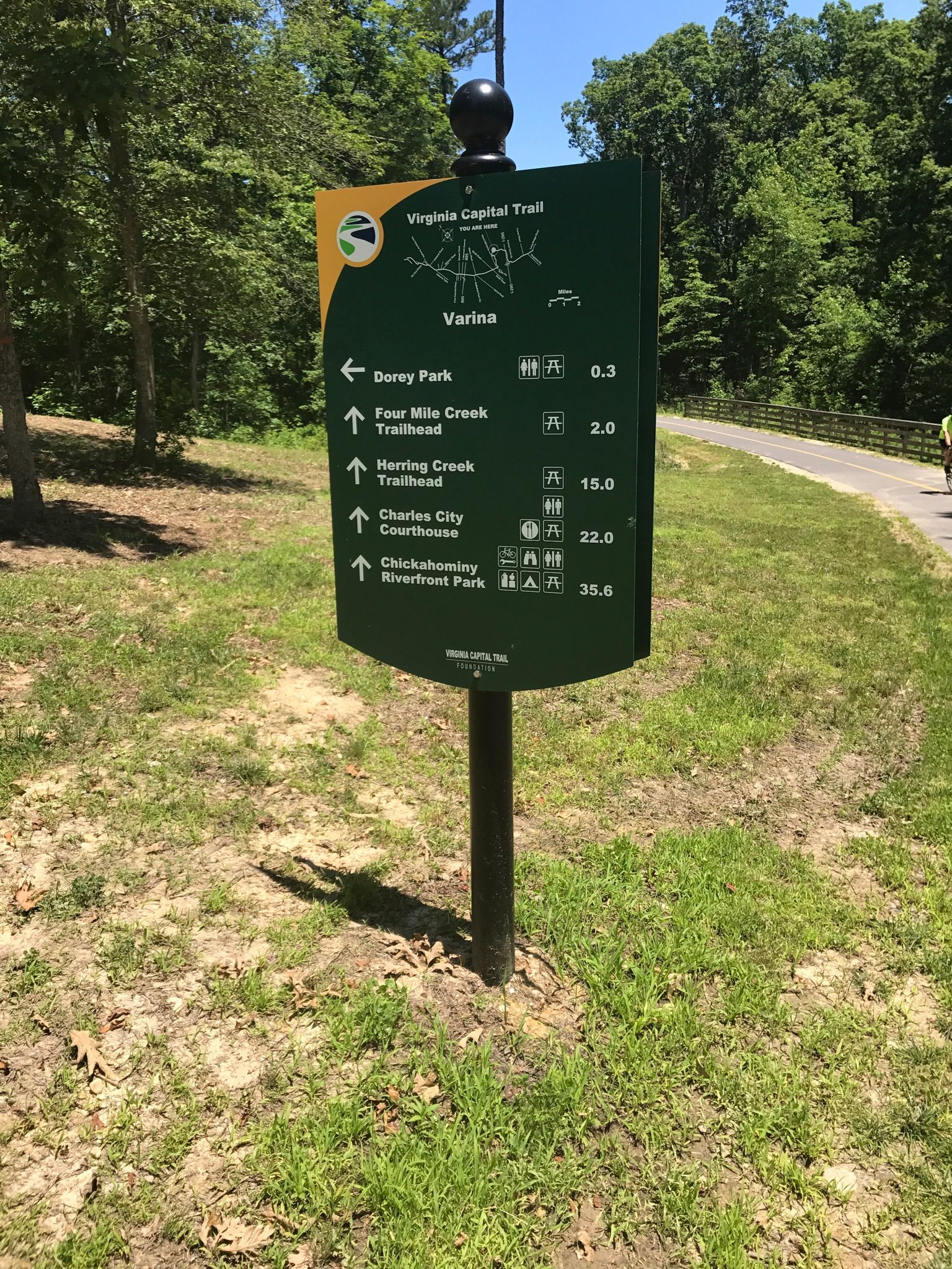 Green trail sign on a post in a grassy area with trees. - Dorey Park Orange Trail