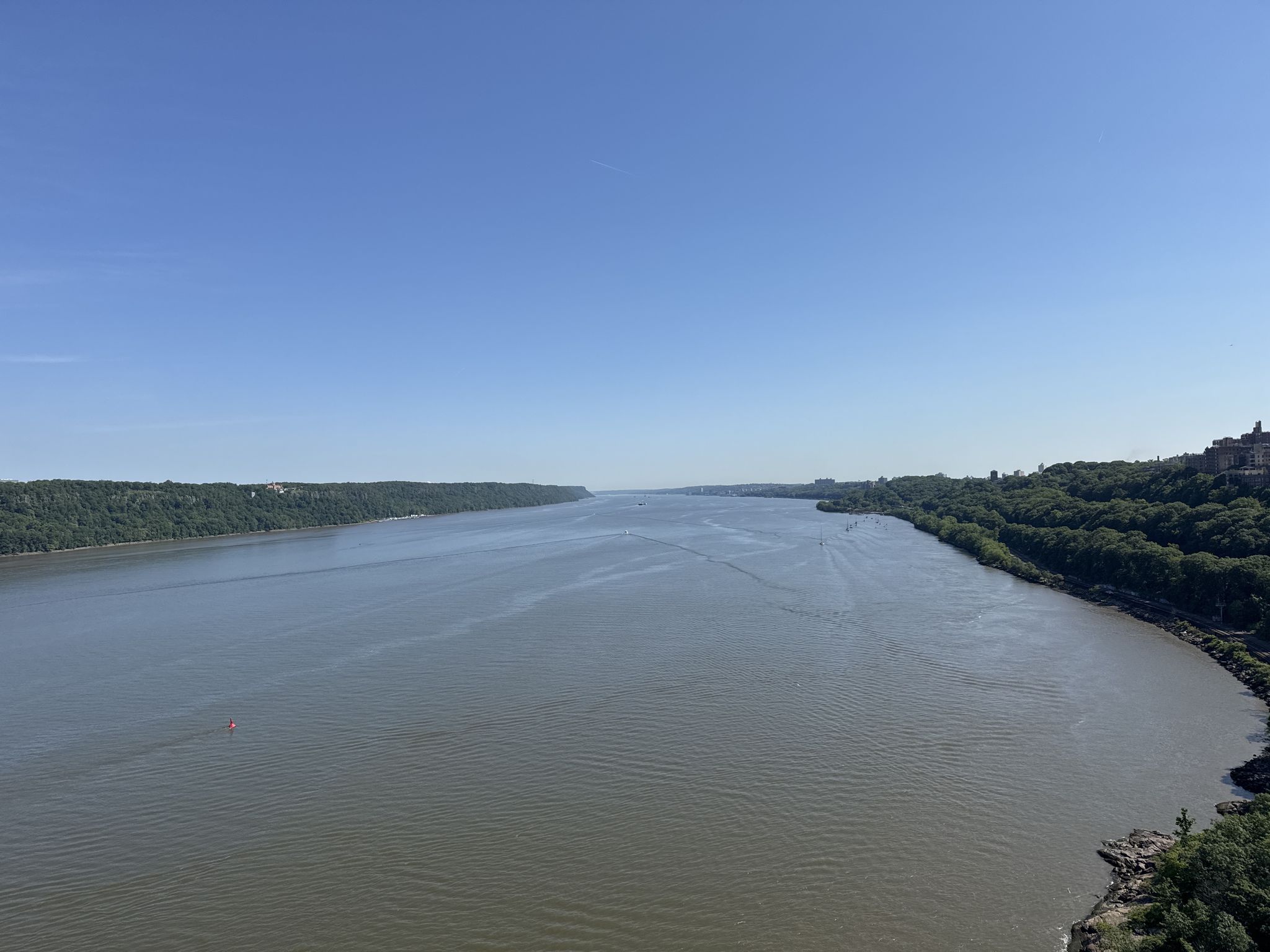 Expansive river with green forested banks under a bright, clear blue sky. - Palisades Interstate Park – Climb up to Alpine loop from Bronxville