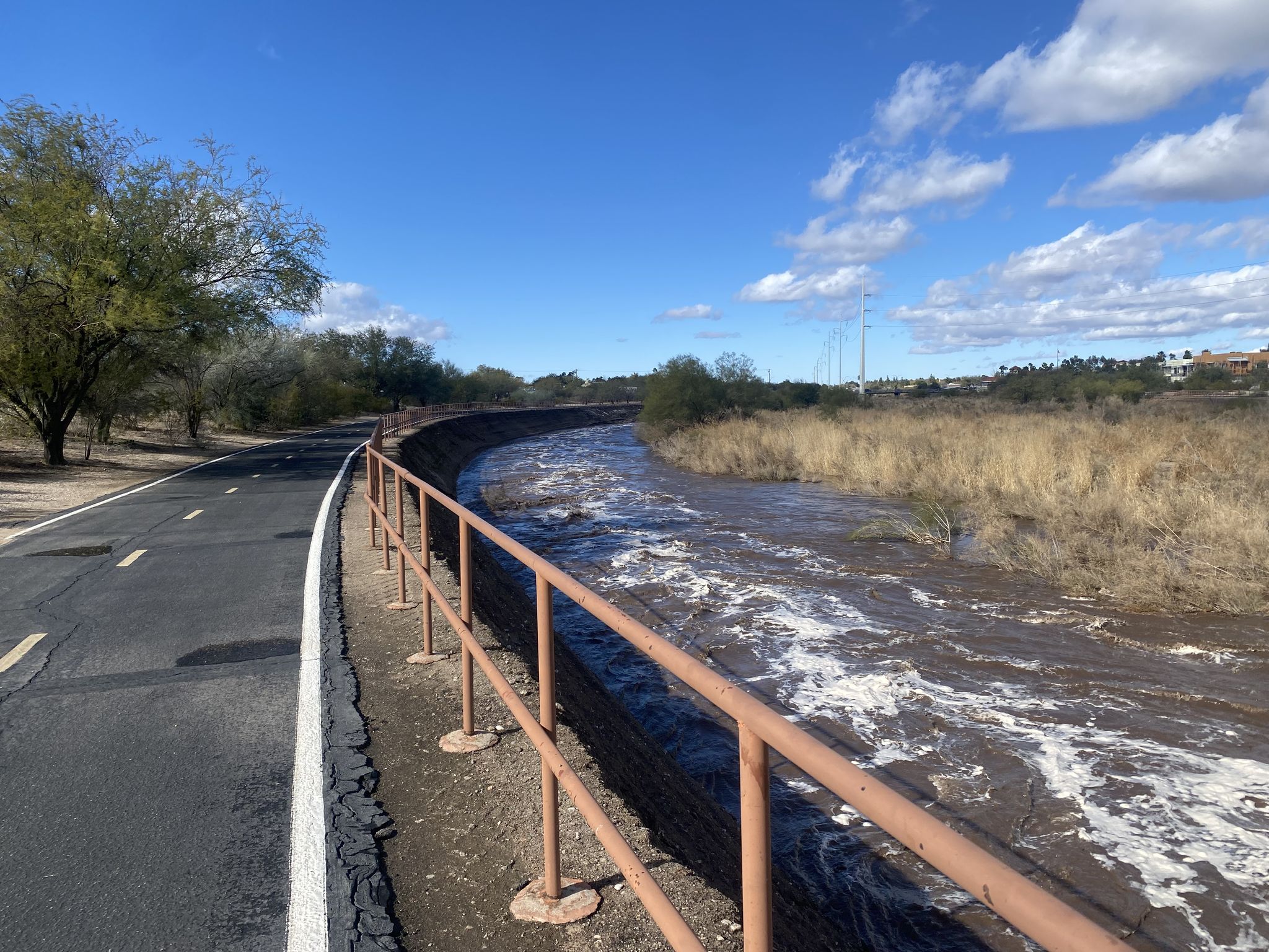 Paved path next to a fast-flowing, muddy river with a metal railing. - Rollito River Path loop from Valley of the Moon