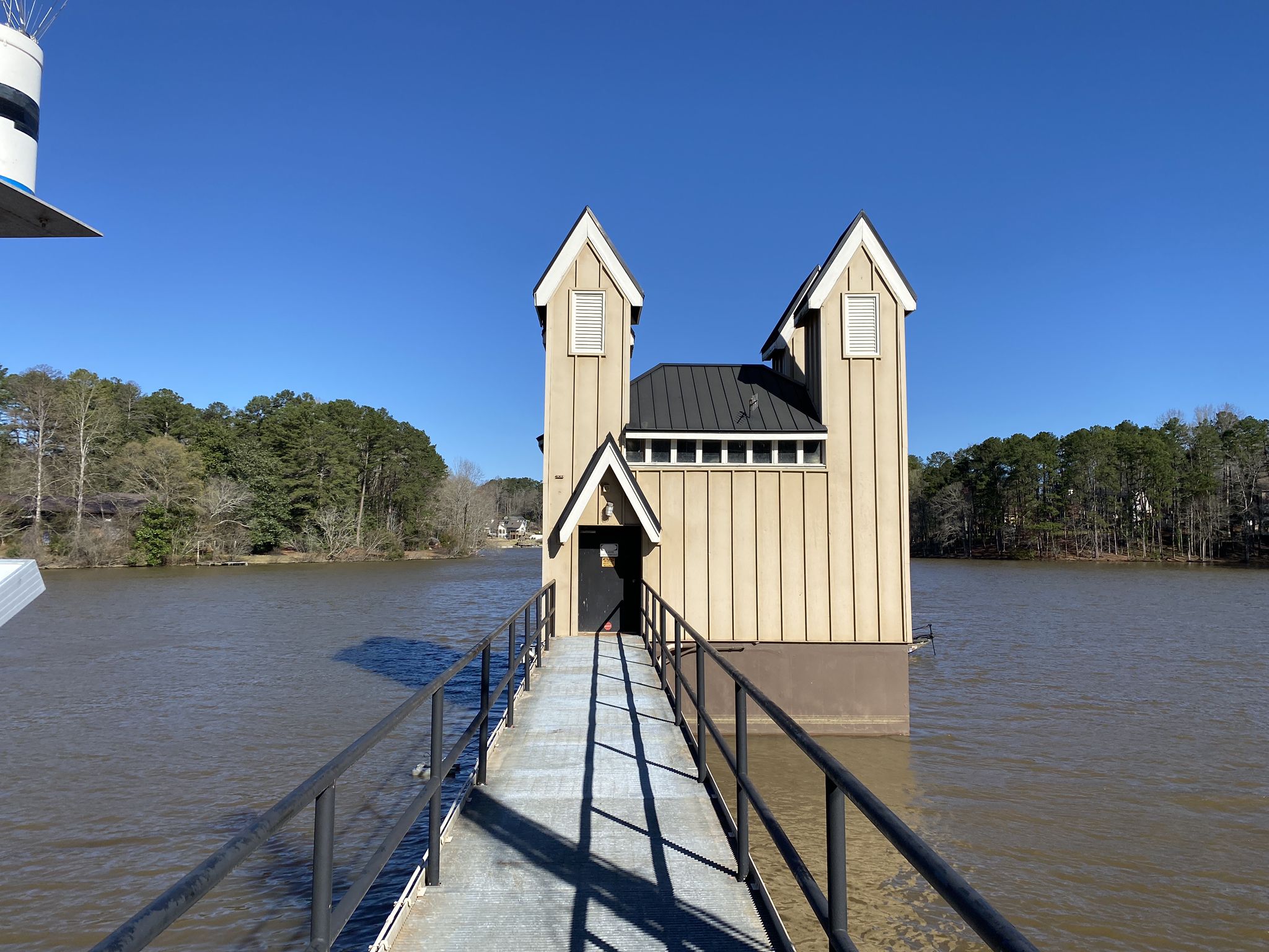 Walkway leading to a unique two-towered building on stilts over a lake. - Lake Peachtree Dam – Lake Peachtree loop from Flat Creek Nature Area Boardwalk
