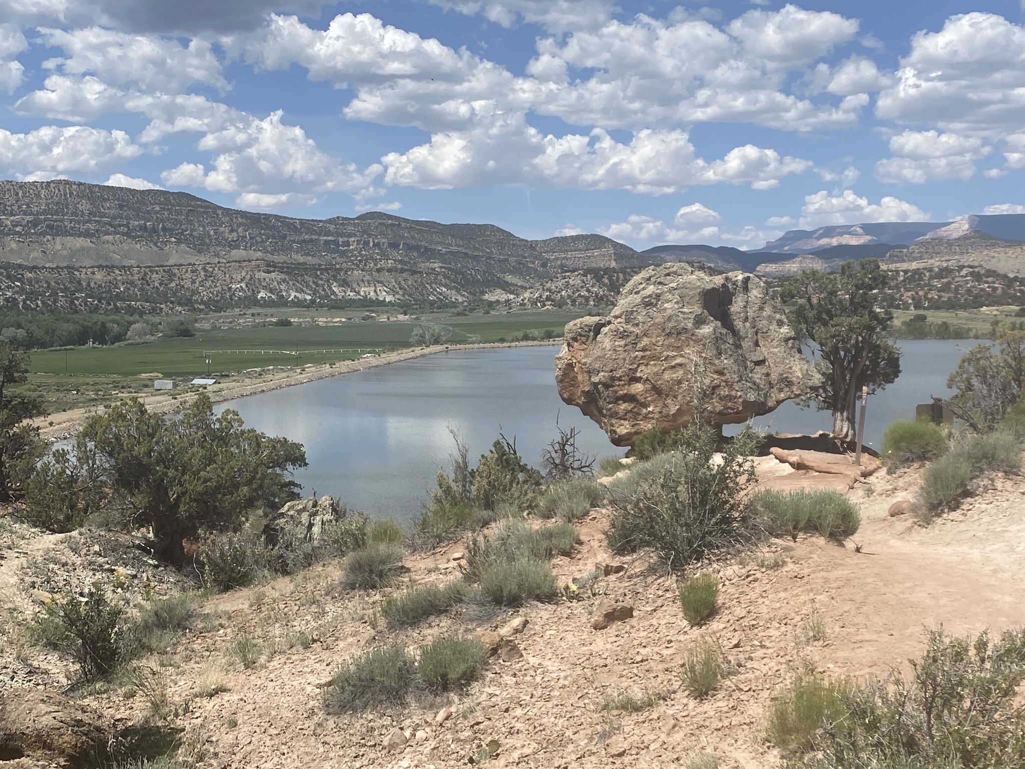 Wide view of a lake with a large rock and tree, mountains in background. - Petrified Forest and Sleeping Rainbows Trail