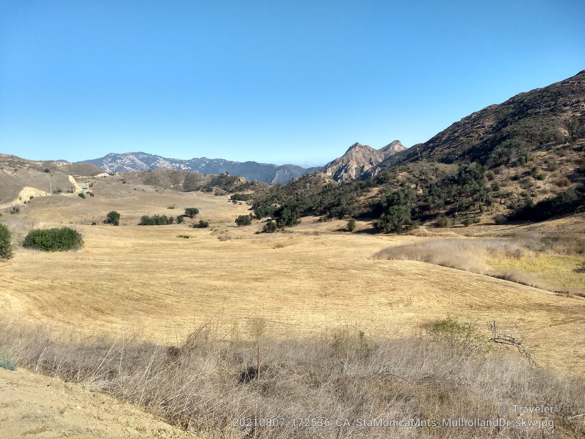 Wide view of a dry valley with distant mountains under a clear blue sky. - Mulholland Highway Loop