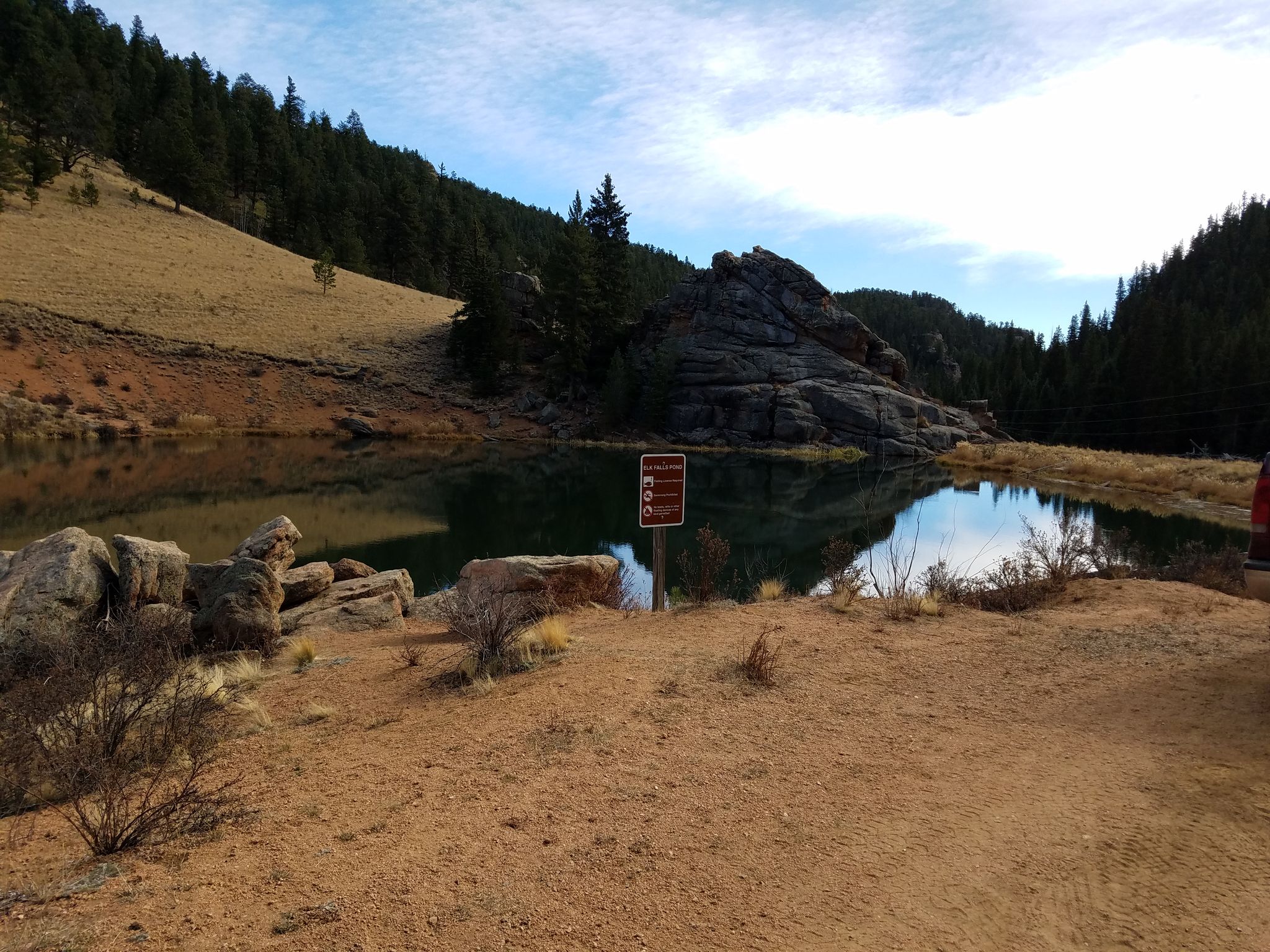 Calm lake reflecting sky, surrounded by rocky hills and pine trees. - Elk Falls Pond and West Meadow Loop Trail via Cub Creek Trail