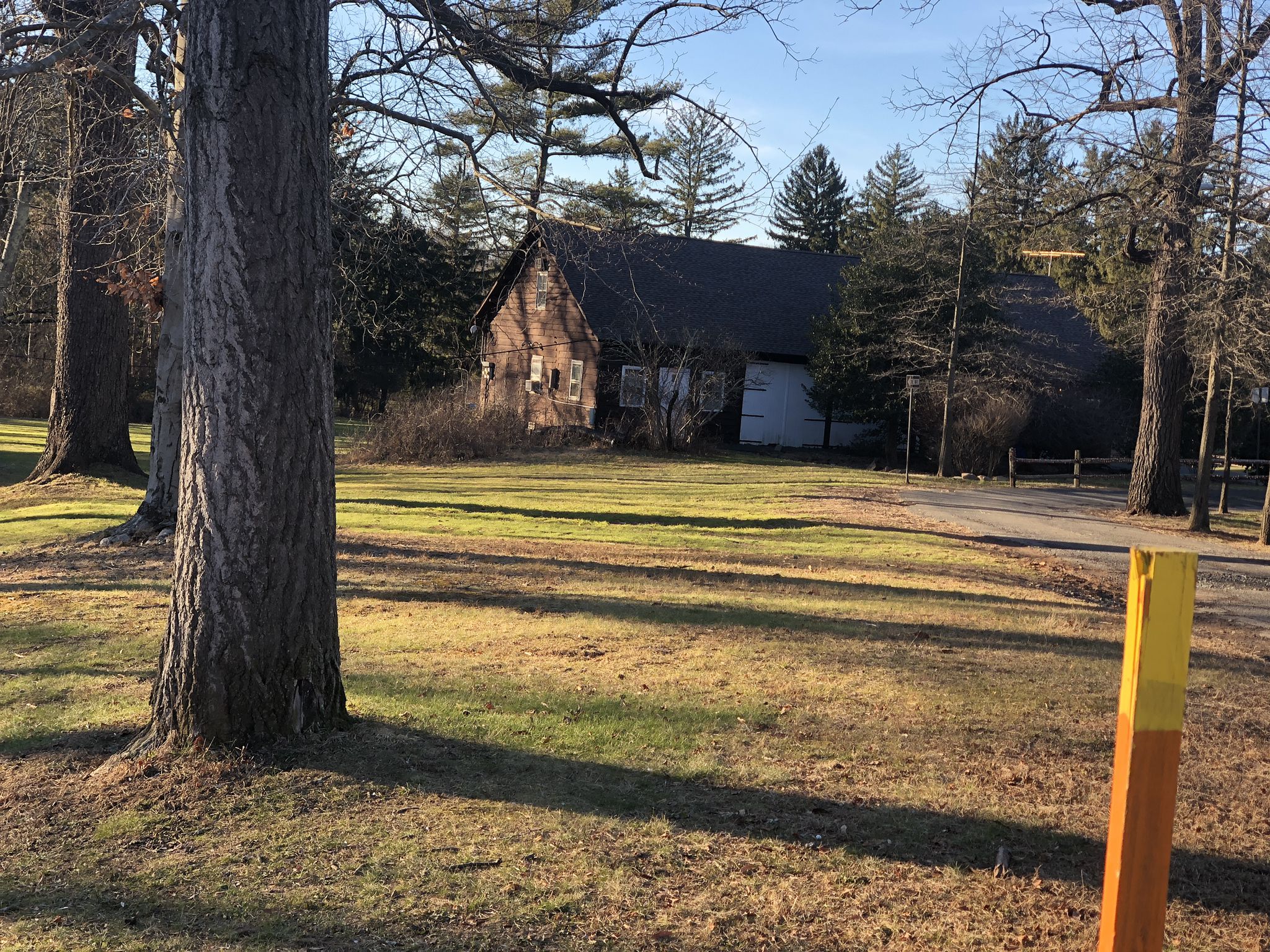 Old wooden barn in a sunny, grassy field surrounded by trees. - Watchung White, Purple and Yellow Trail Loop