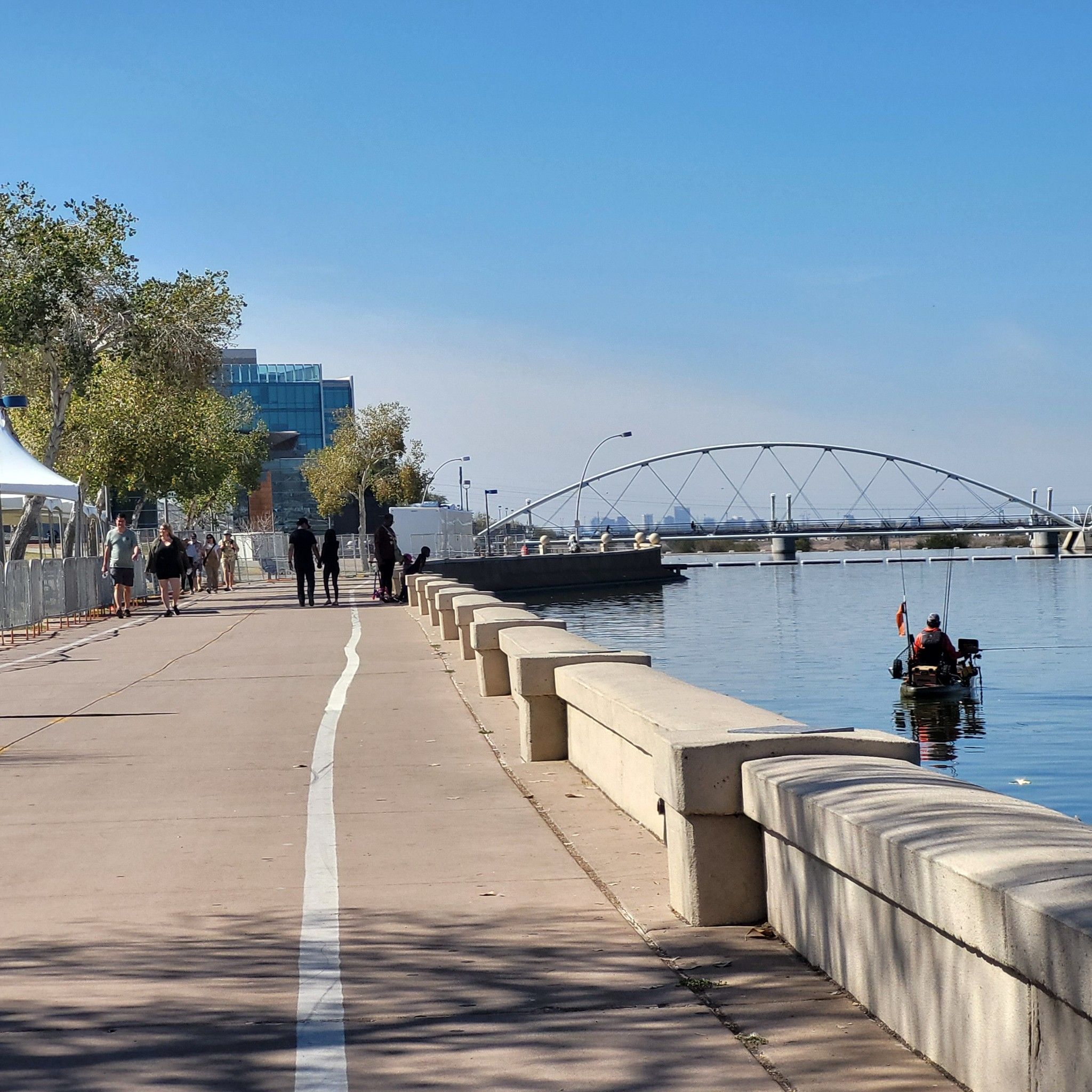 People walking on a path, kayaker on water, and a bridge, sunny. - Rio Salado Pathway