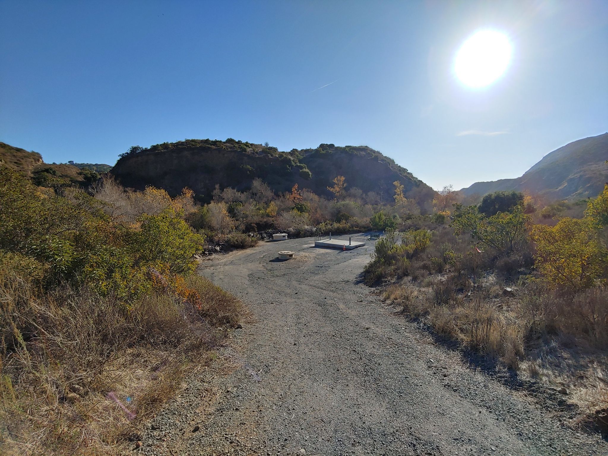 Gravel path leading into a sunny valley with hills and sparse vegetation. - Visitor Center and Oak Grove Loop