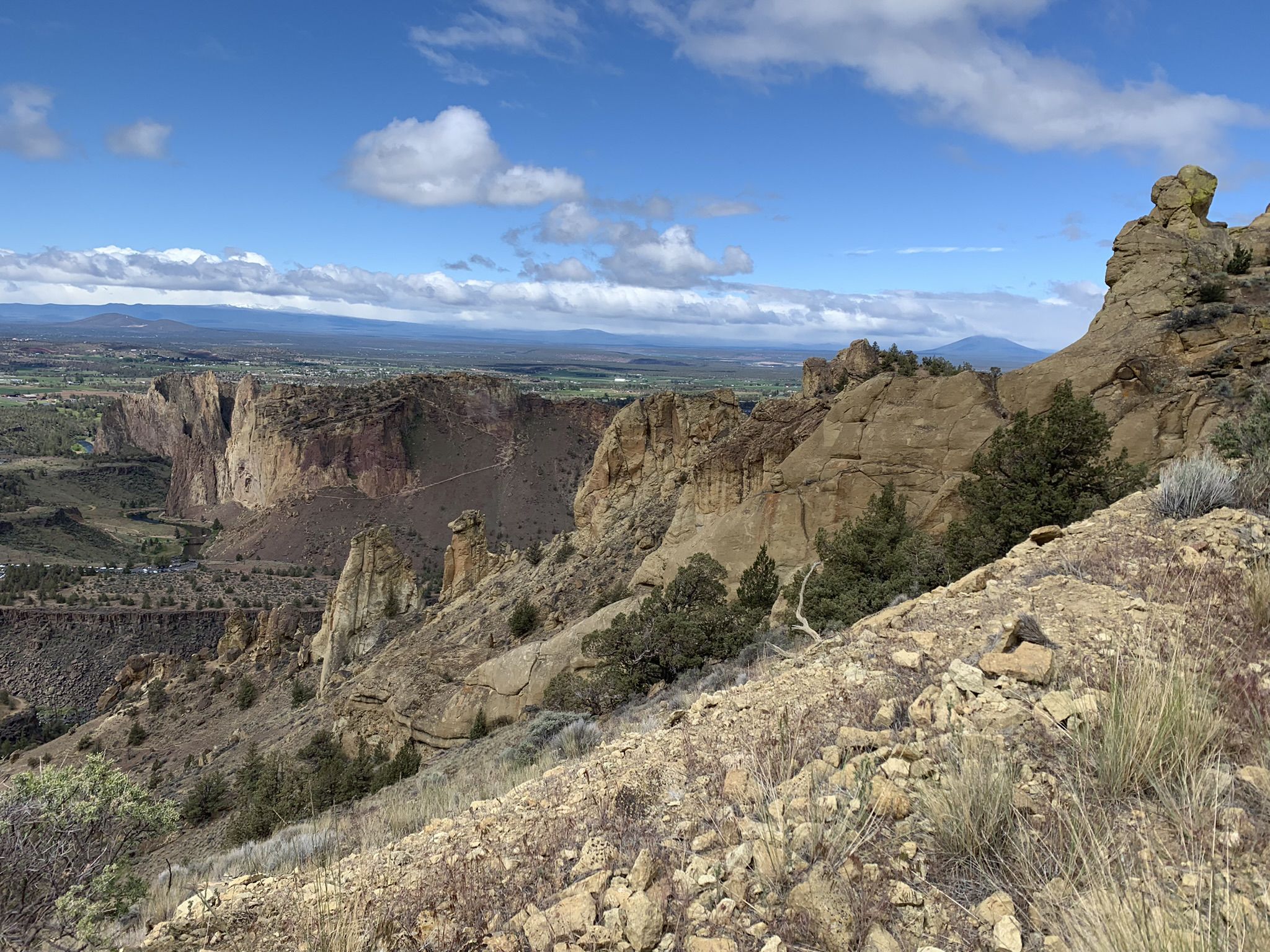 Sunny view of a deep canyon with rugged rock formations and a distant valley. - Sisters to Smith Rock Scenic Bikeway Loop