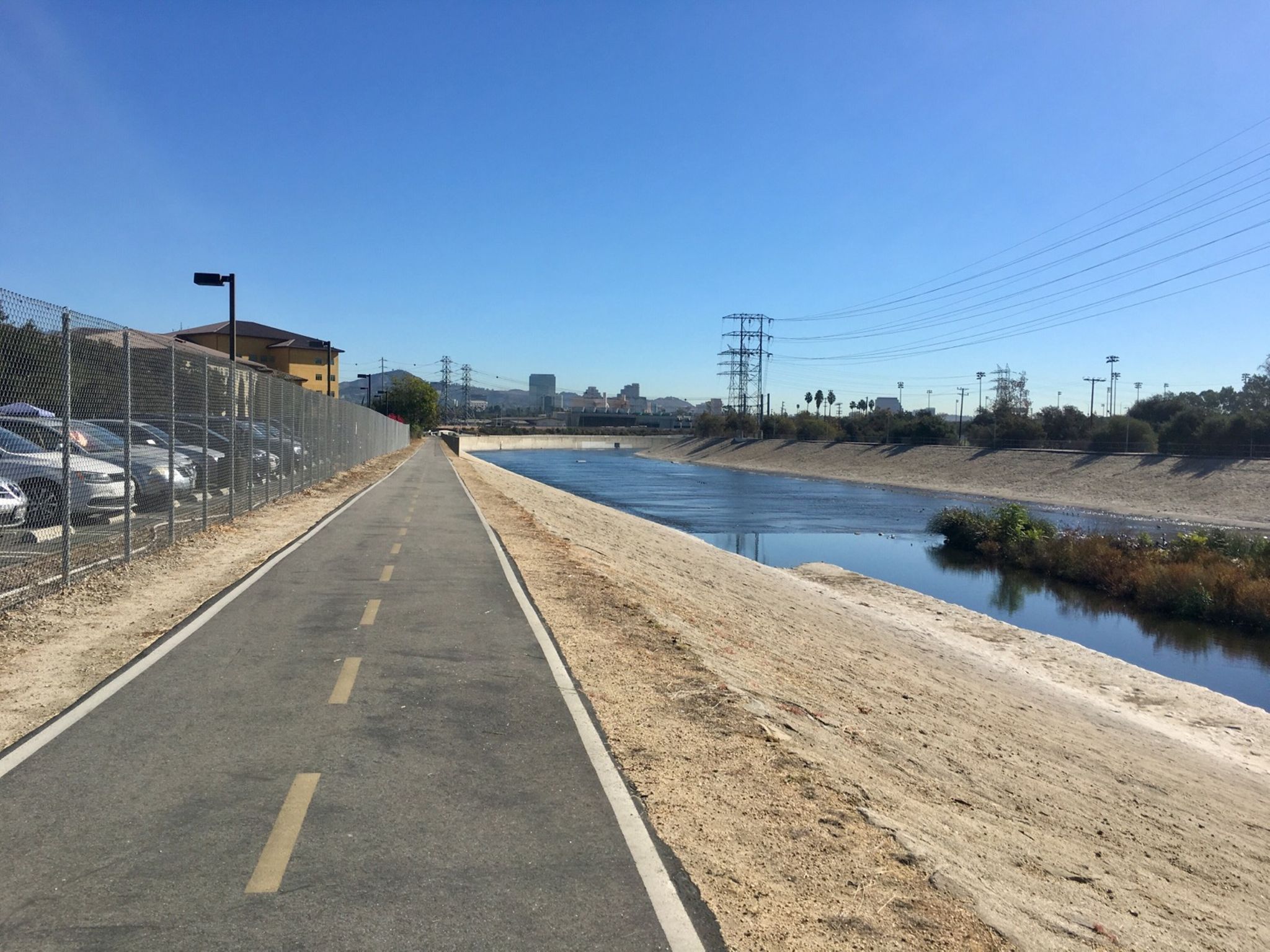 Paved path beside a wide concrete channel with water, power lines, sunny. - Lacy Park – Arroyo Seco Bike Trail loop from Allen