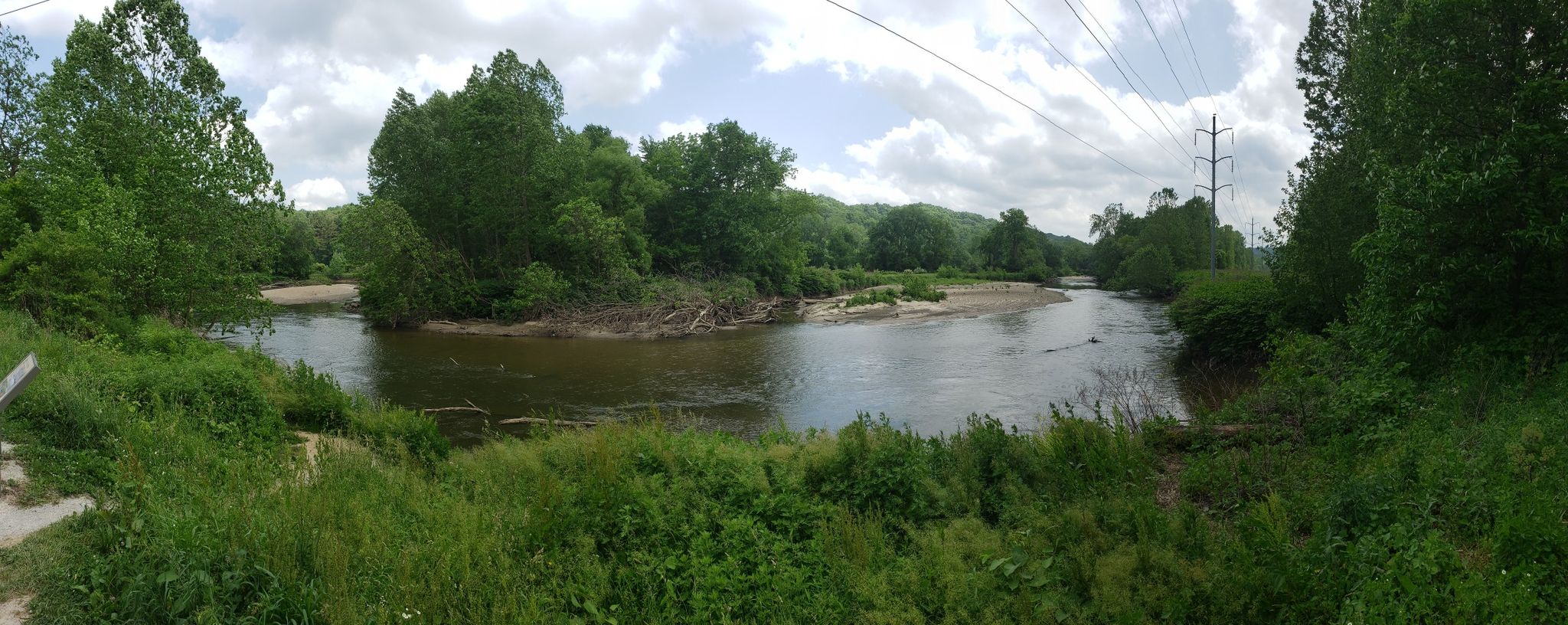 A wide river with green banks and distant hills under a cloudy sky. - Nice covered bridge – Szalay's Farm & Market loop from Akron Northside