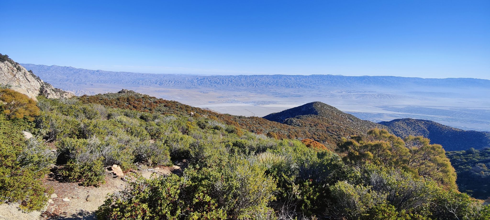 Expansive desert mountain landscape with a hazy valley under a clear blue sky. - Skyline Trail